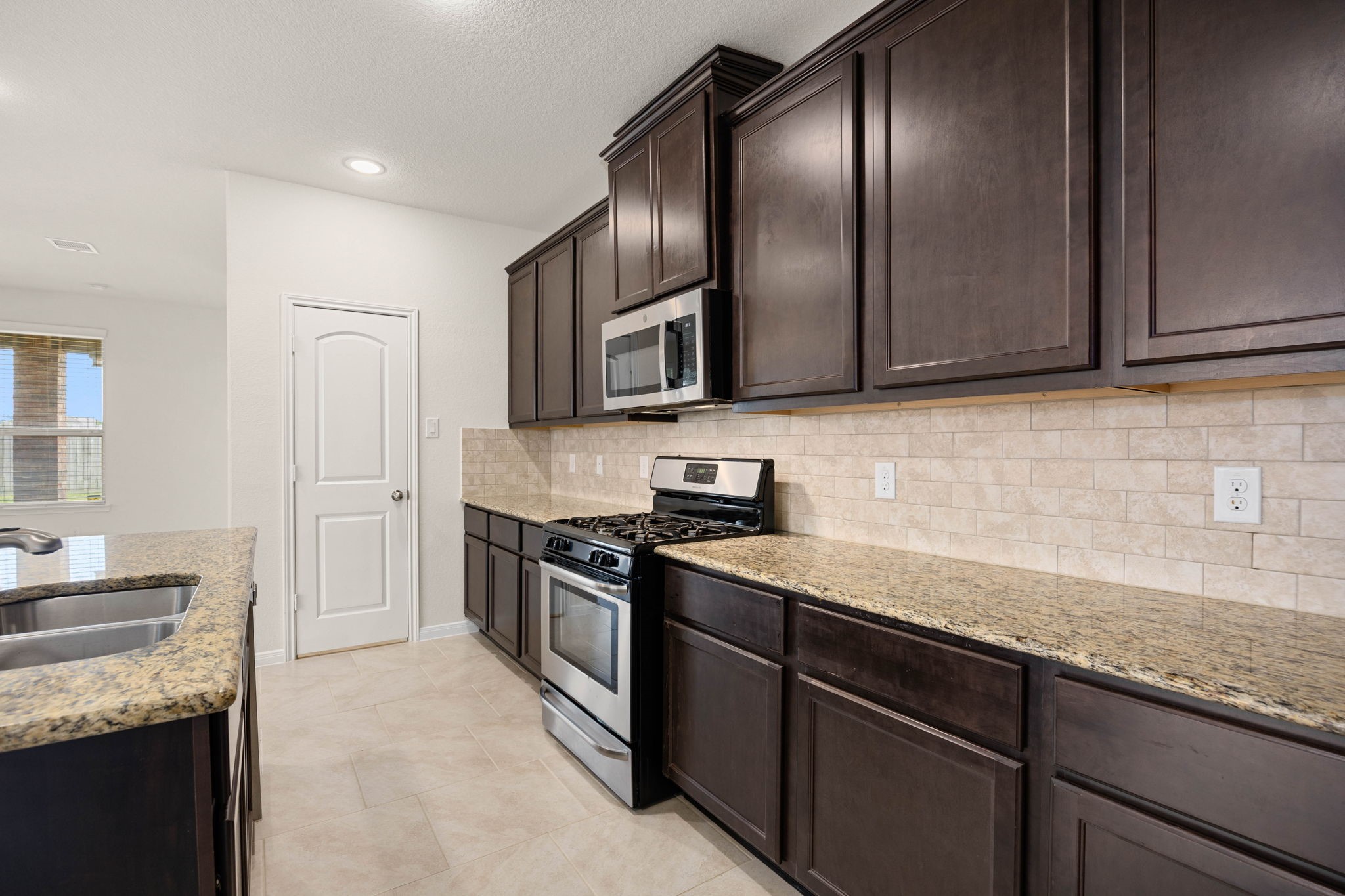 This thoughtfully crafted space balances functionality with an inviting atmosphere. The main counter run flows effortlessly toward a spacious kitchen island, ensuring the chef remains part of the conversation. Whether you are hosting holiday gatherings or preparing quiet weeknight dinners, this kitchen serves as a cozy, high-functioning hub tailored for modern living.