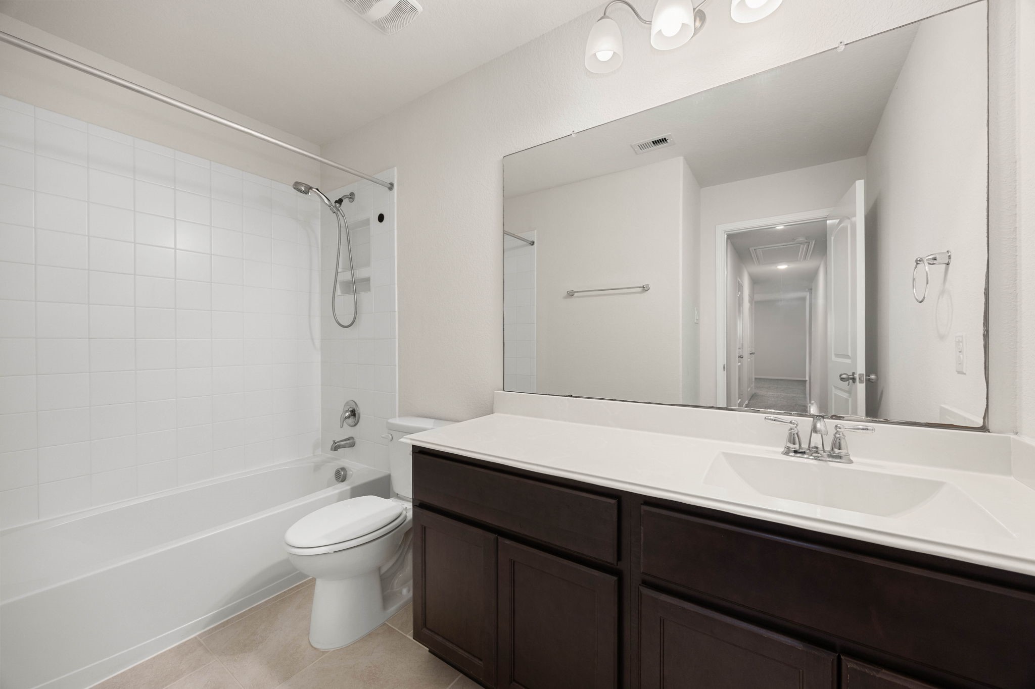 Pristine secondary full bathroom highlighting an expansive single-sink vanity, rich modern cabinetry, and a clean tub-to-ceiling tile surround.