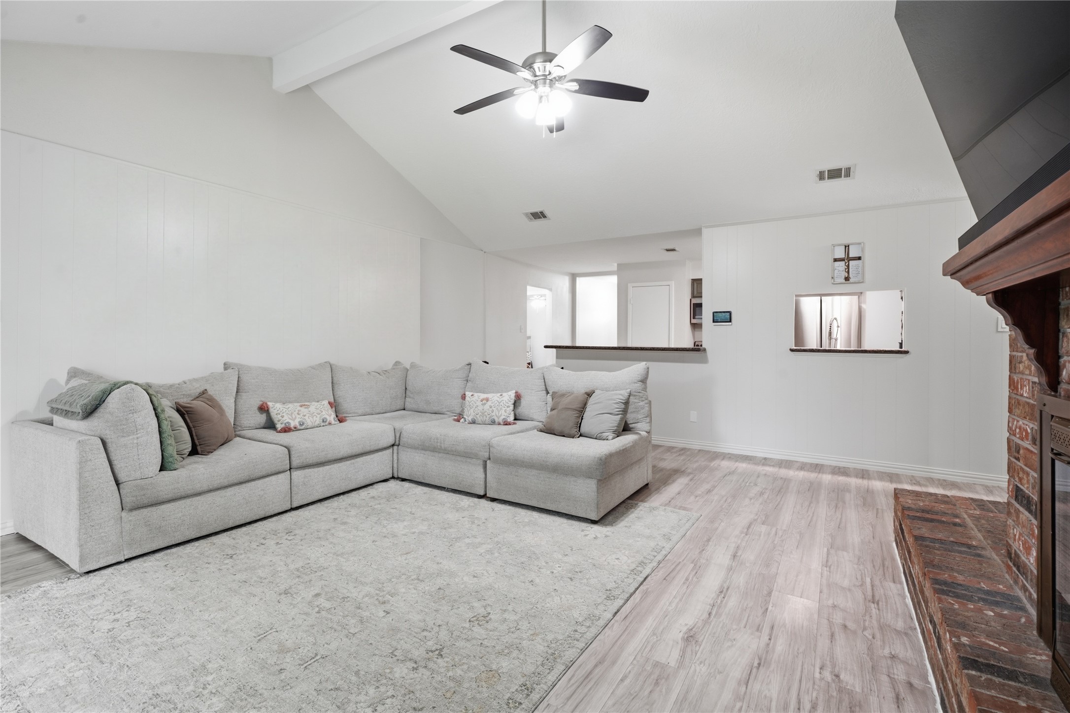 Spacious living room with vaulted ceilings, wood-look flooring, and an open layout that flows seamlessly to the kitchen.