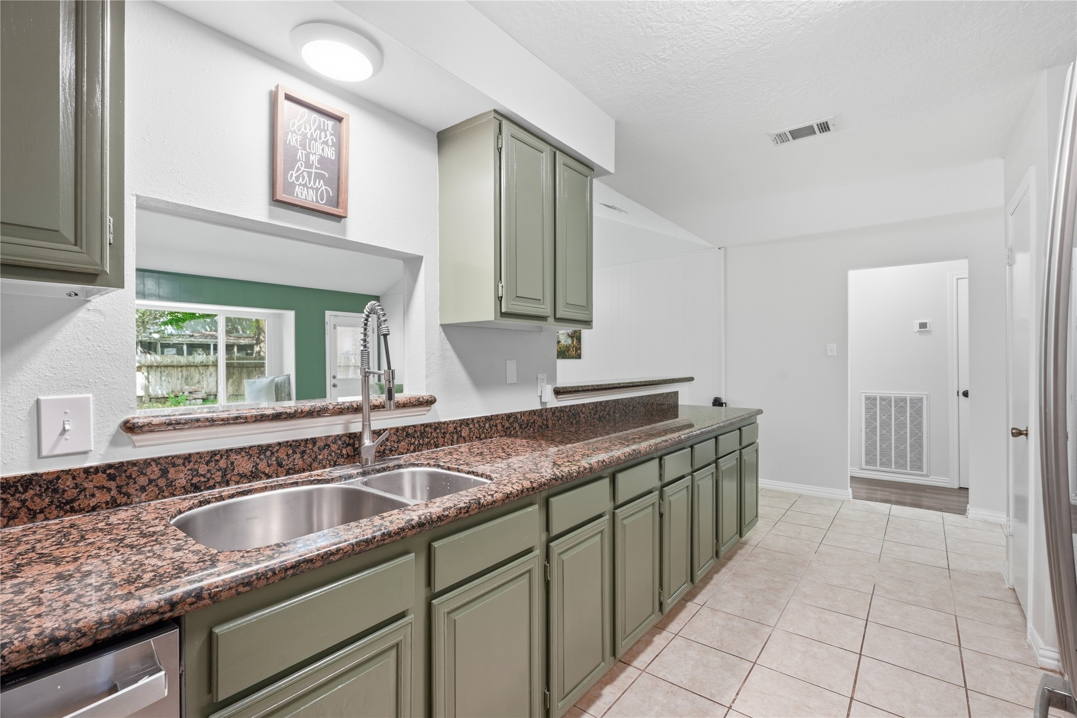 Kitchen featuring an oversized breakfast bar, double-basin sink with pull-down faucet, and an open pass-through overlooking the living room. Kitchen featuring an oversized breakfast bar, double-basin sink with pull-down faucet, and an open pass-through overlooking the living room.