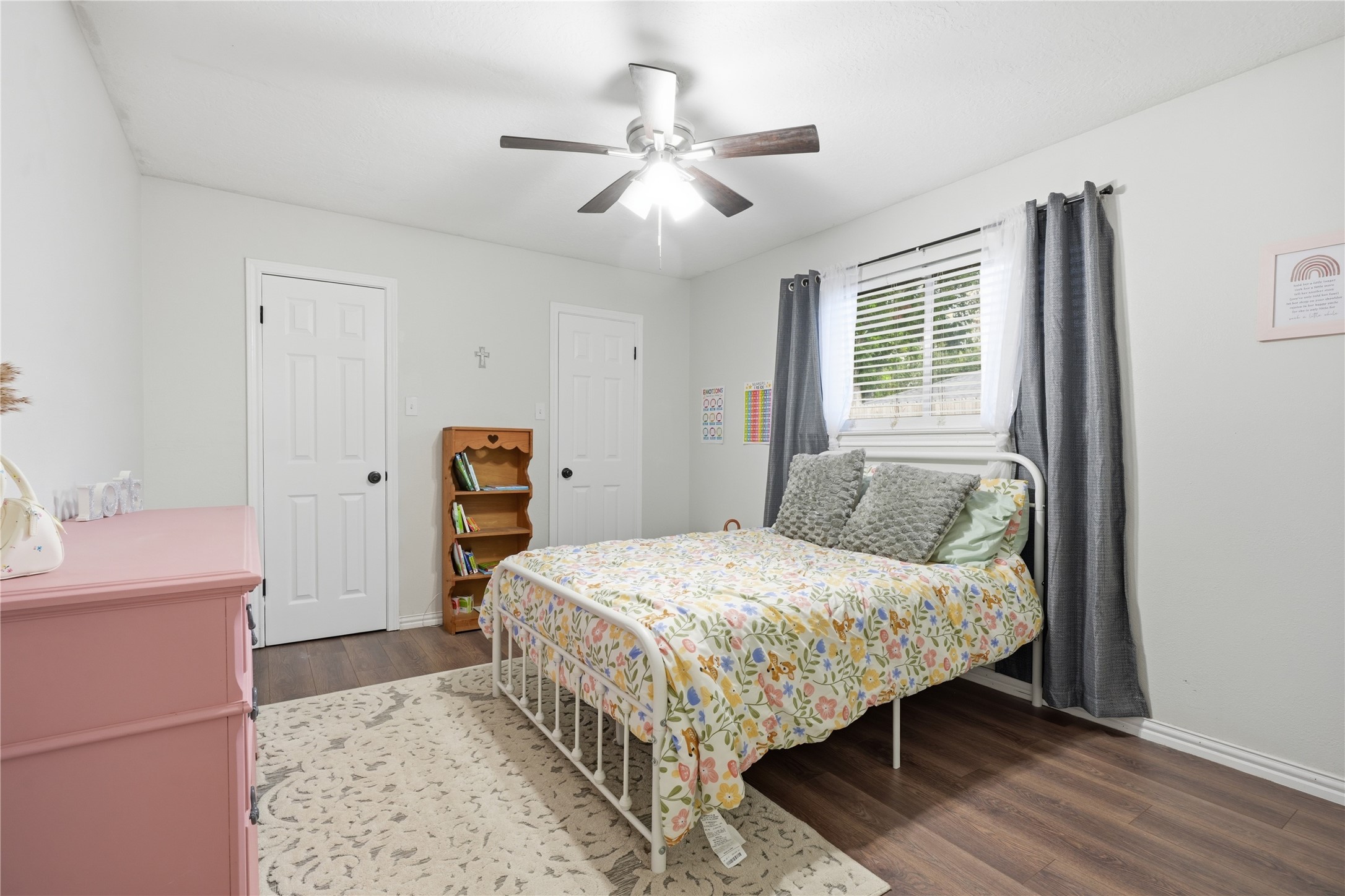Comfortable secondary bedroom with wood-look flooring, ceiling fan, large window, and closet for ample storage.