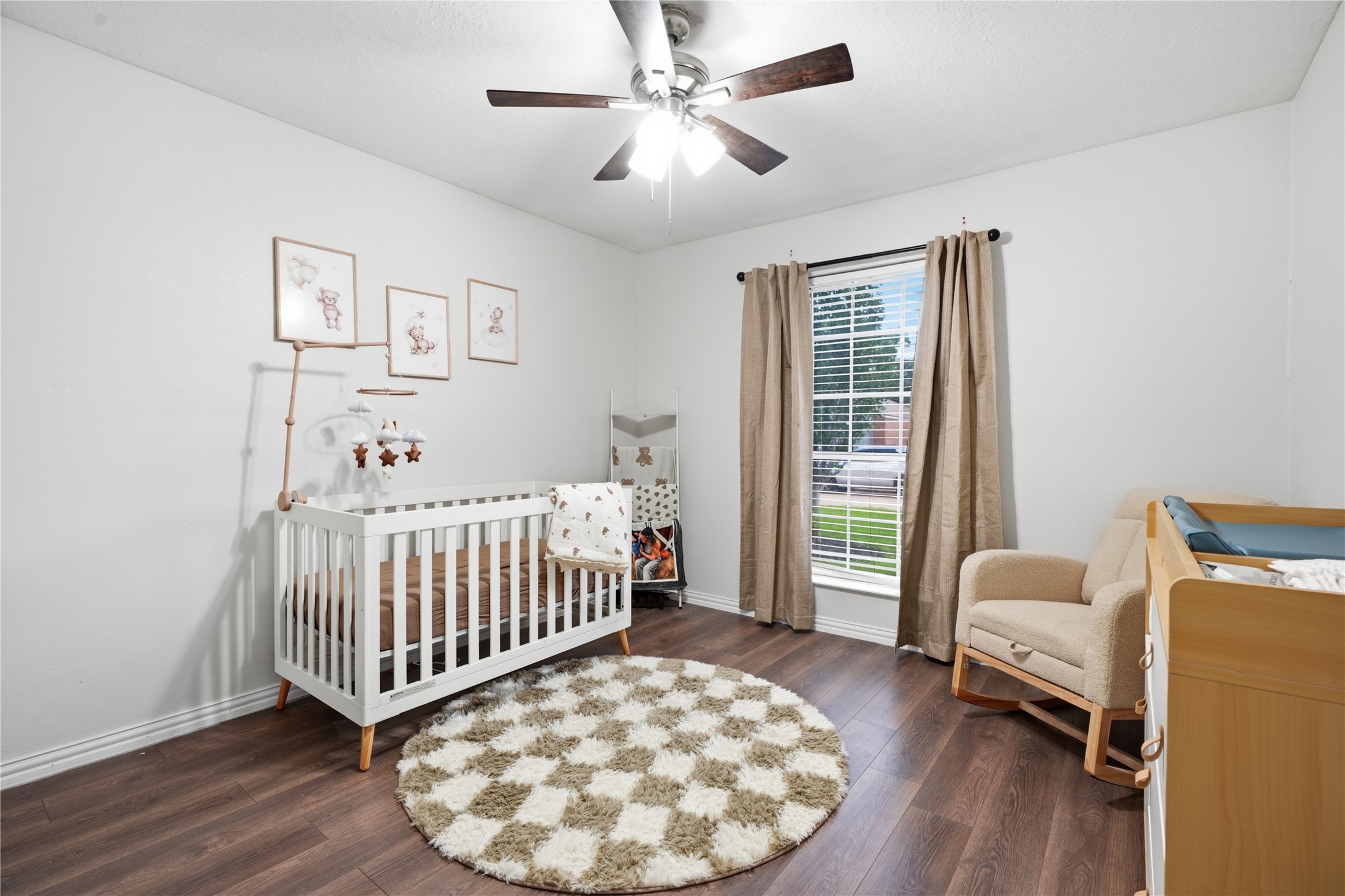 Bright secondary bedroom featuring wood-look flooring, a ceiling fan, large window for natural light, and a spacious closet.