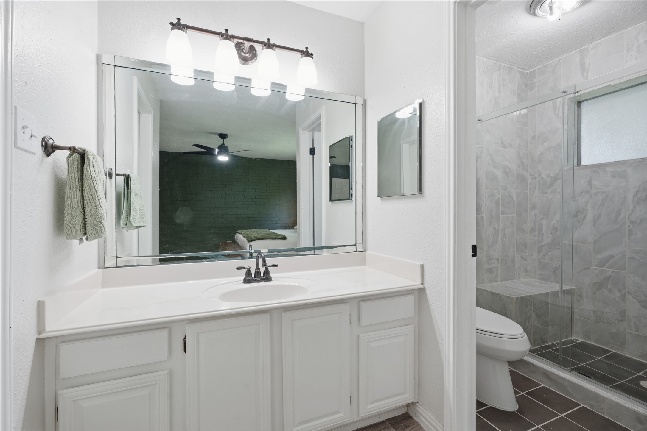 Primary bathroom featuring an oversized vanity with ample counter space, updated lighting, and direct access to the custom walk-in shower.