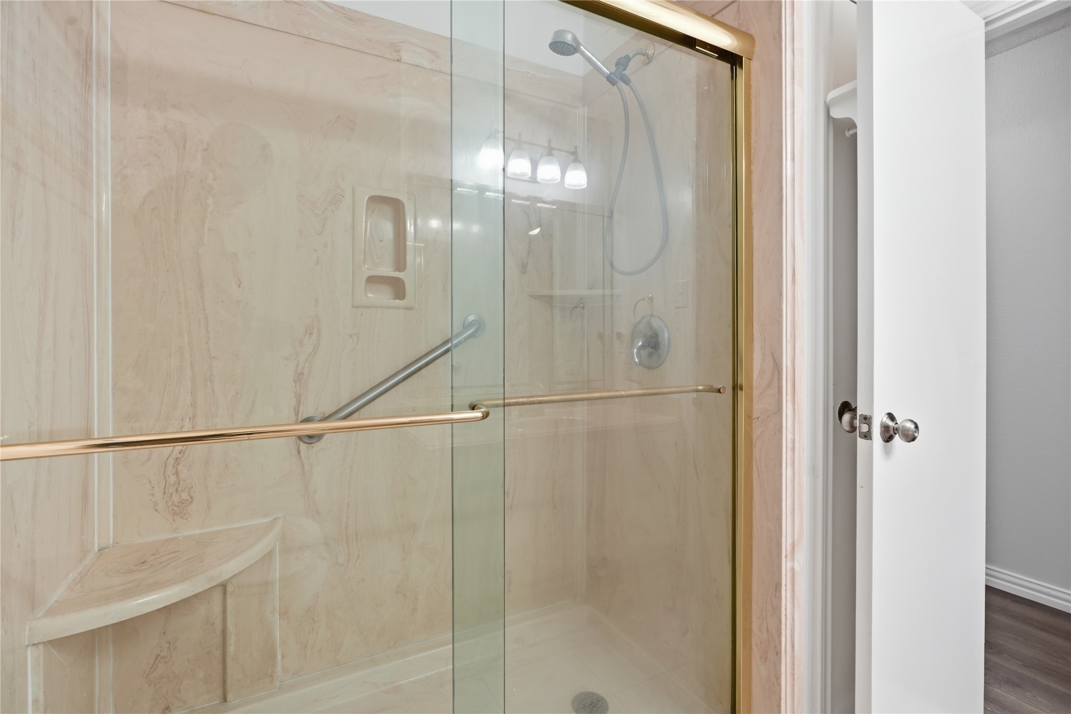 Secondary bathroom with a walk-in shower featuring sliding glass doors, built-in seating, and grab bars for added convenience.