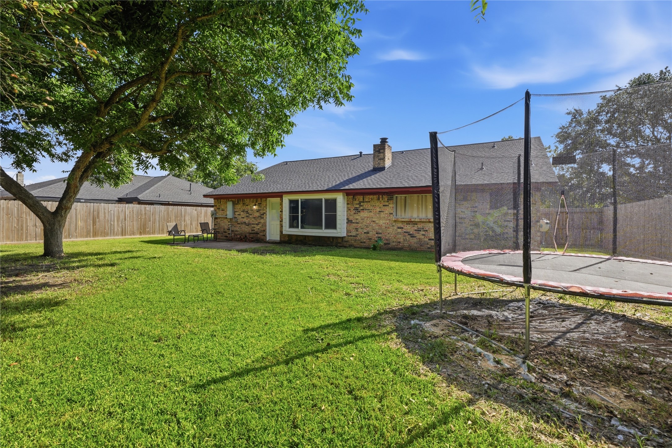 Expansive fenced backyard with mature shade trees, plenty of green space, and room for outdoor activities.