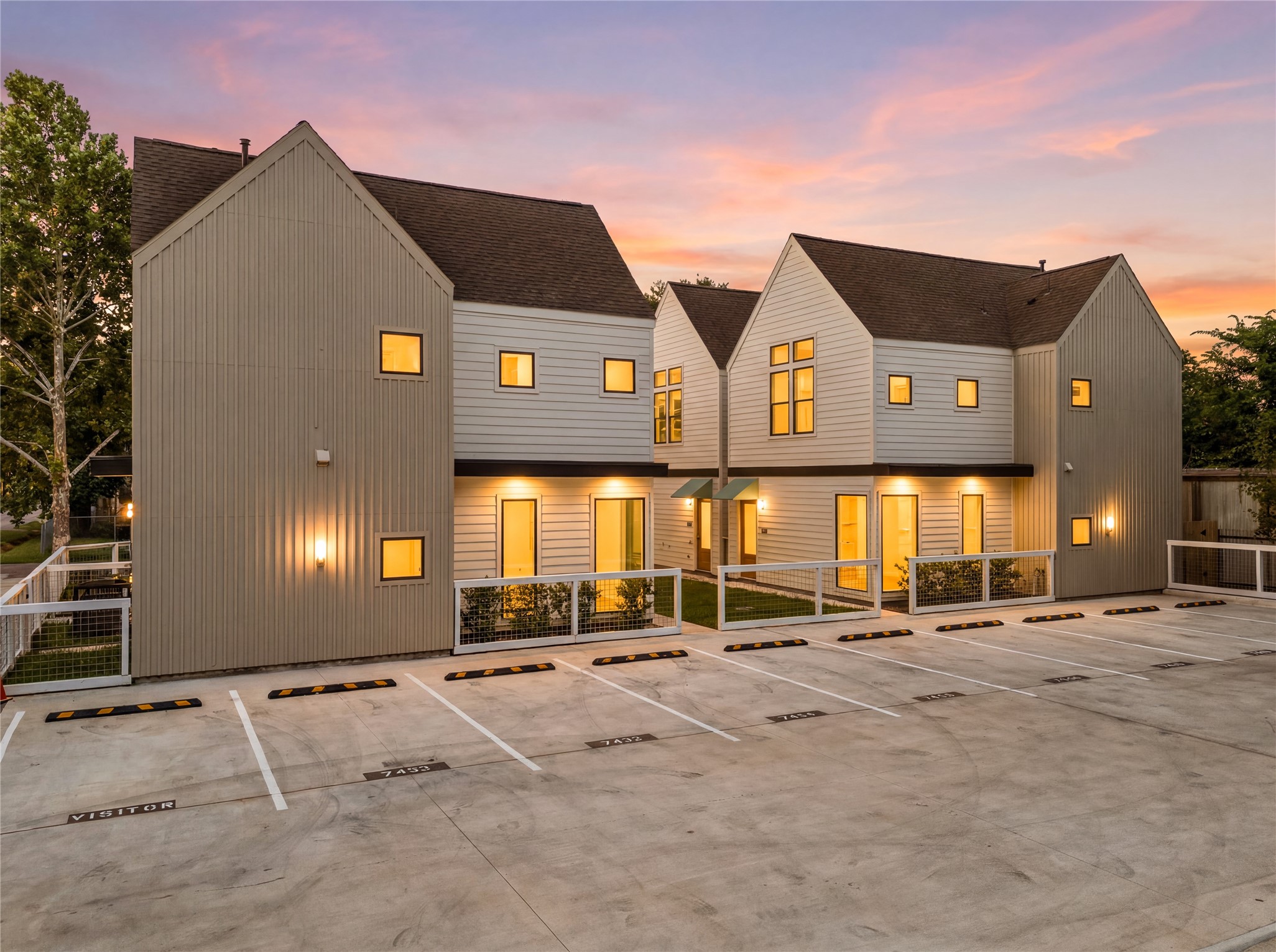 Stunning twilight view showcasing warm exterior accent lighting and open parking spaces.