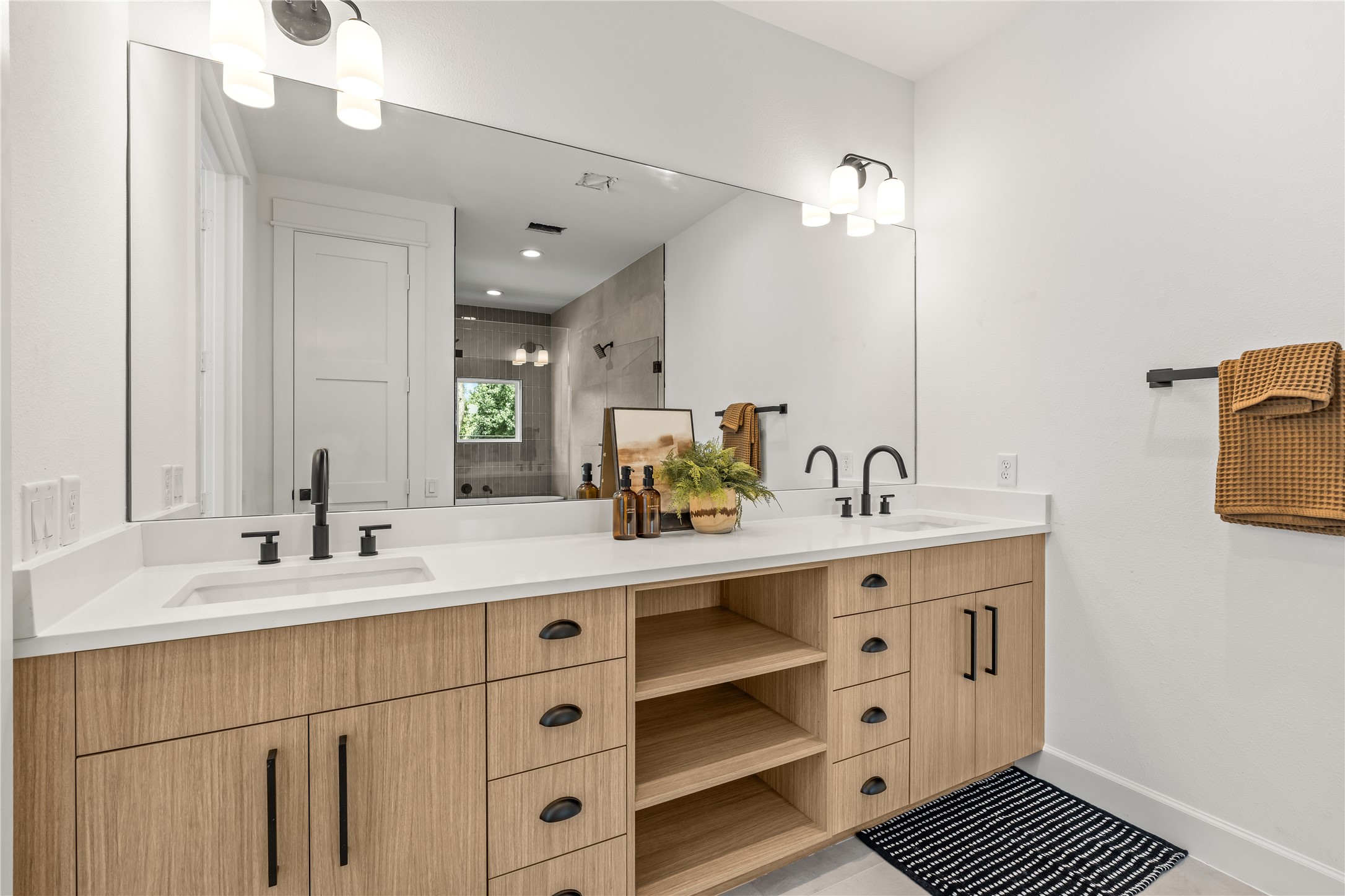 Perspective view of the primary bathroom vanity highlighting the large frameless mirror and modern dual light fixtures.
