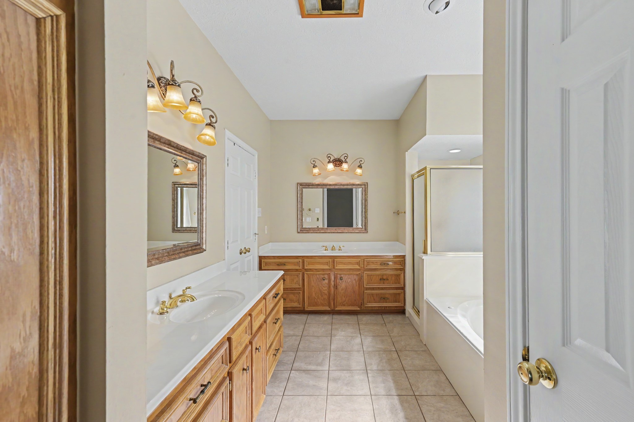 Spacious primary bathroom with dual sinks and wooden cabinetry, a relaxing soaking tub, & separate shower. LOTS of storage throughout!