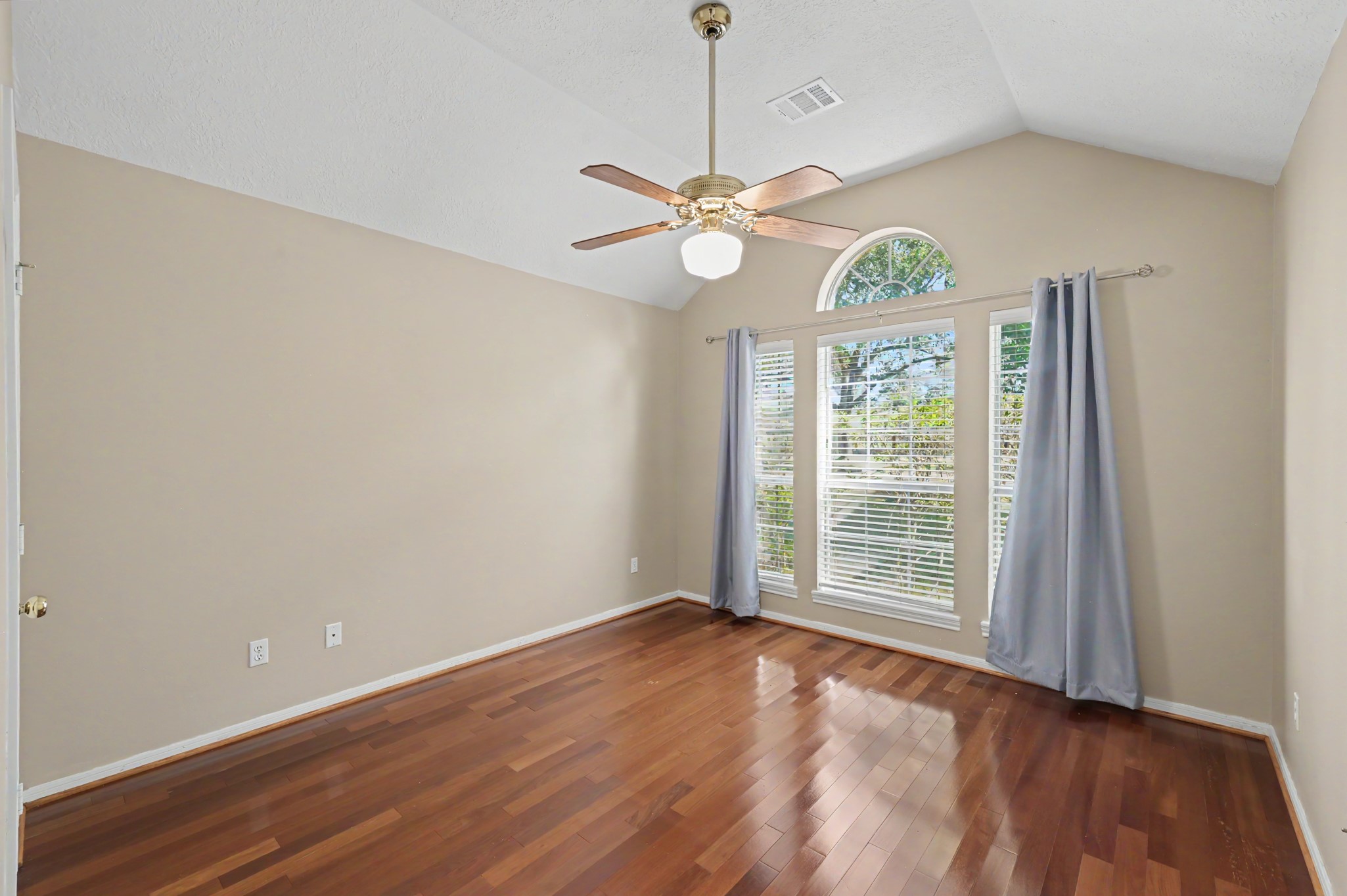 Bright and inviting second bedroom with vaulted ceilings, bathed with natural light, & elegant hardwood floors. Walk-in closet.