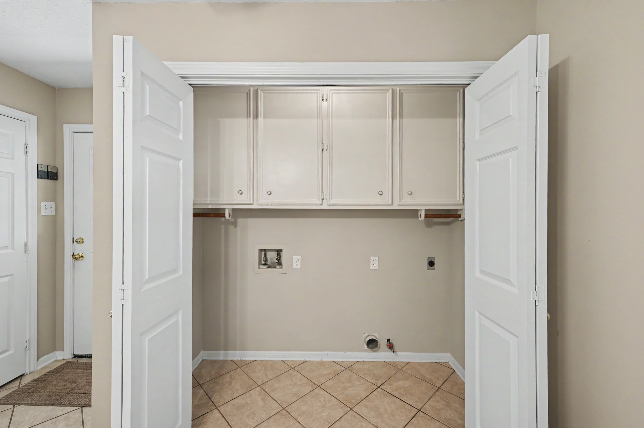 Convenient laundry space with built-in cabinets and tile flooring, ready for your washer and dryer setup.