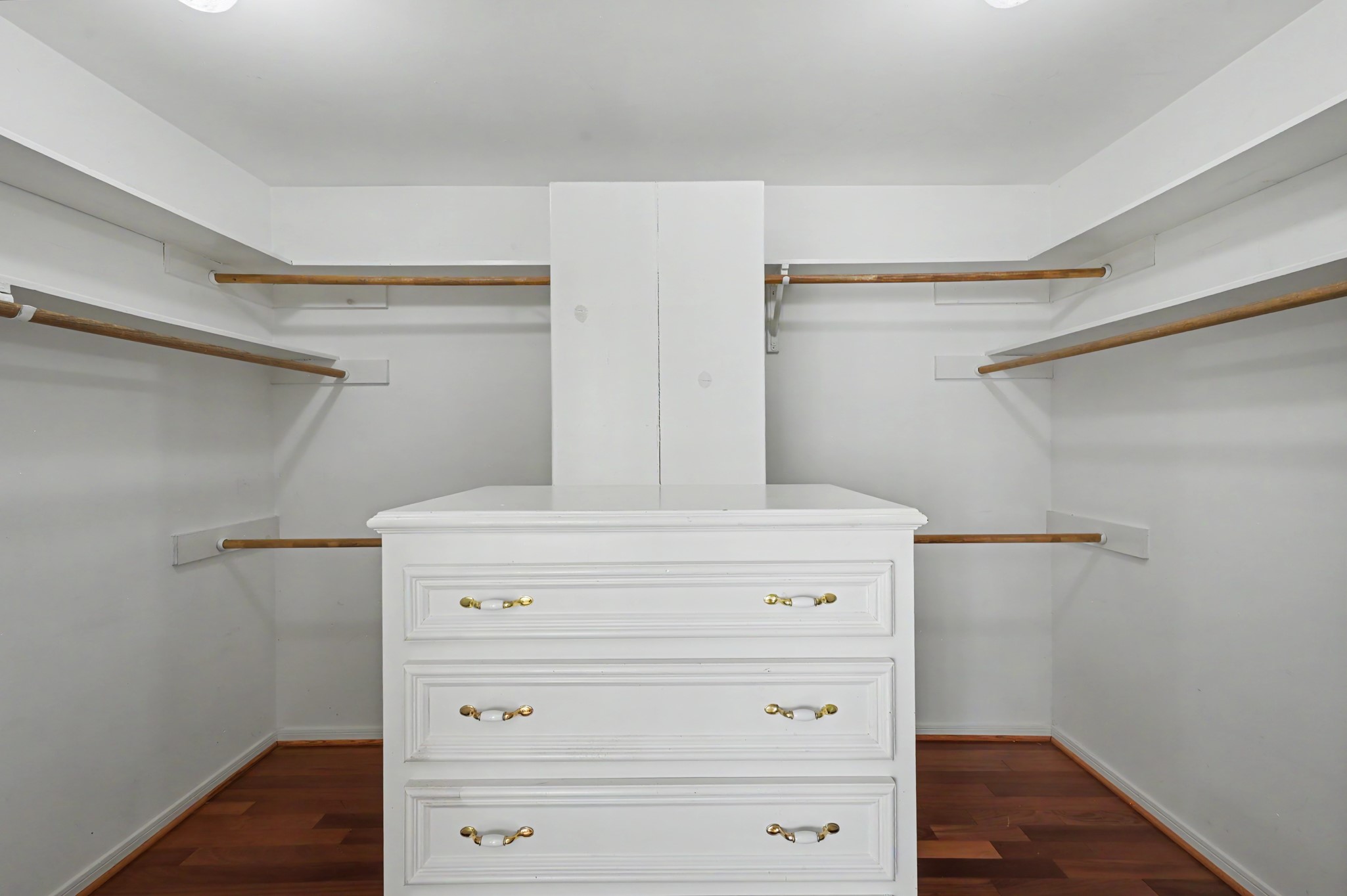 Spacious primary walk-in closet featuring ample hanging space and a central storage island for all your belongings.