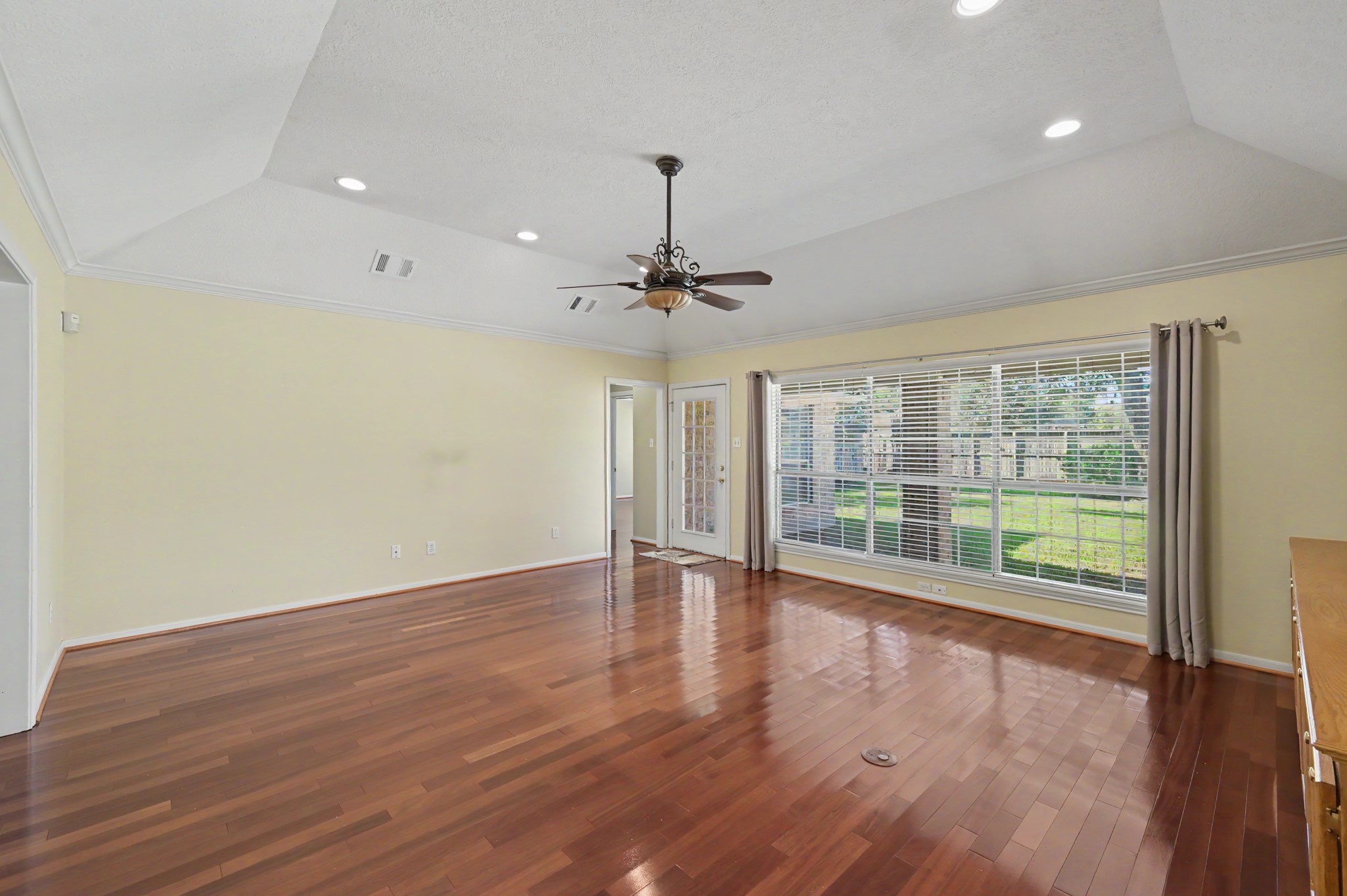 Another view of the living area with rich hardwood floors, vaulted ceiling, and abundant natural light streaming through large windows overlooking the beautiful and oversized backyard.