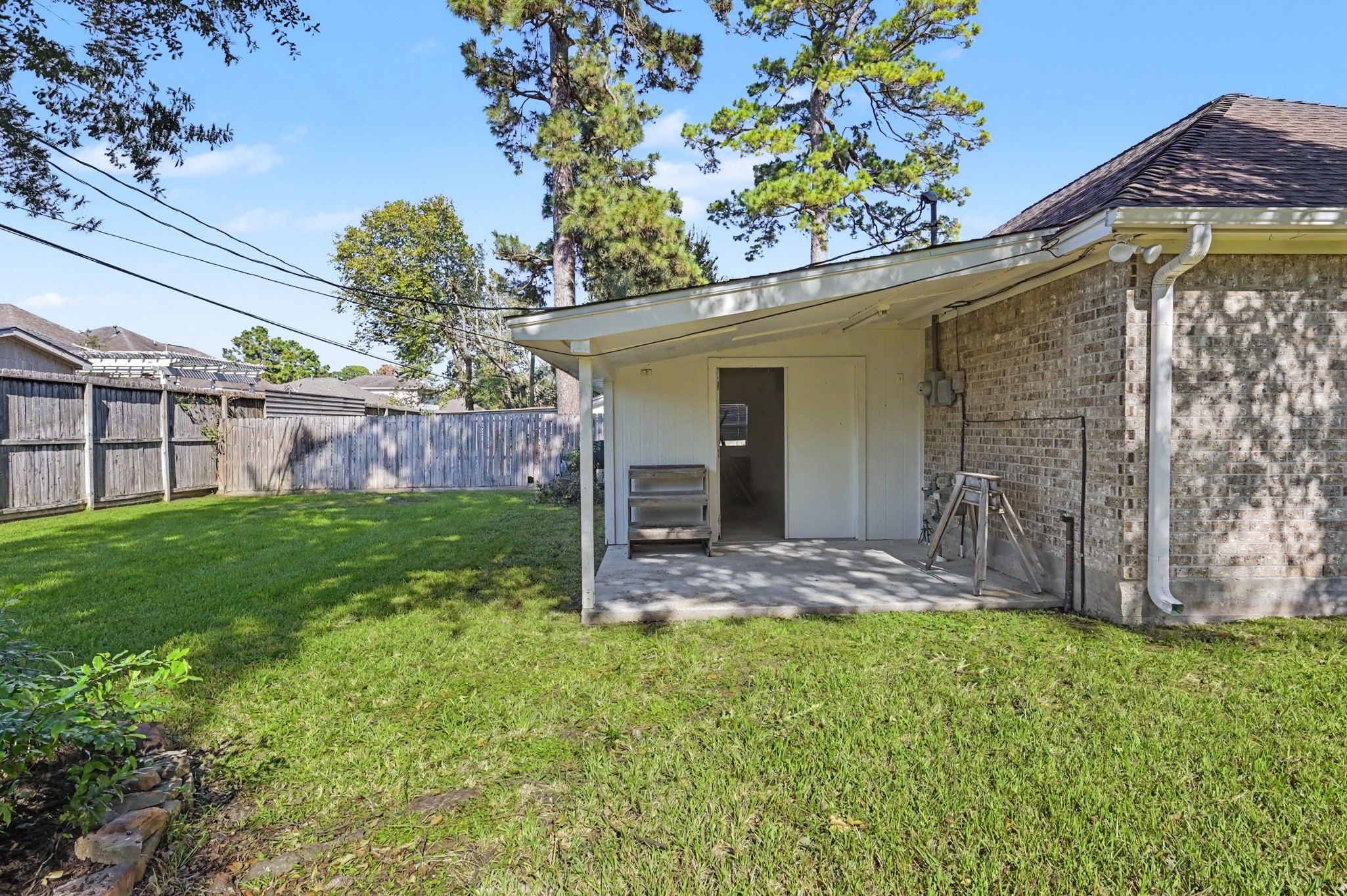 View of the workshop off the back of the garage, surrounded by a privacy fence and mature trees.