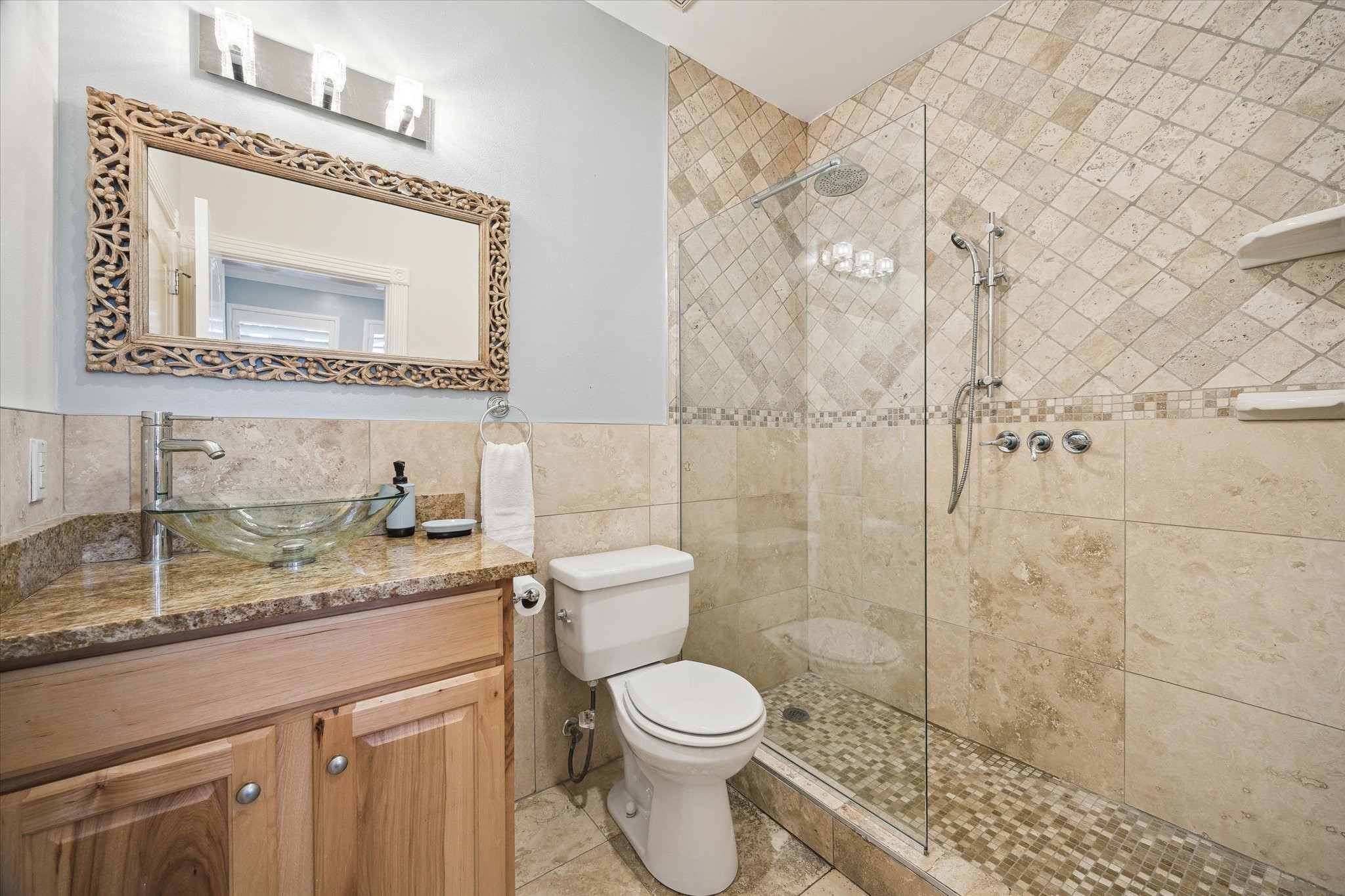 The bathroom is adjacent to the first floor bedroom, features a modern design with stone tile walls. The bathroom has access from the bedroom and the hallway.