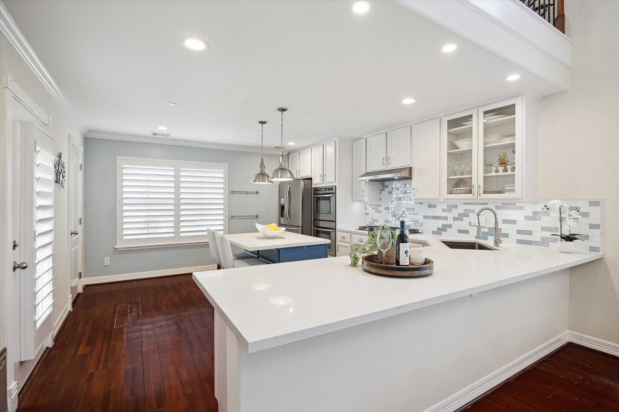 Updated kitchen with white cabinetry, stylish tile backsplash, and stainless steel appliances. It has a spacious island with seating. It opens  to the dining/living room, easy for entertaining.