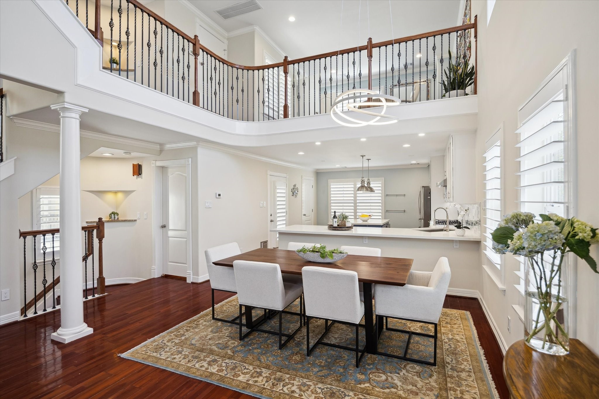 Dining and kitchen area with high ceilings and abundant natural light. The elegant wood flooring and modern fixtures create a warm, inviting atmosphere.