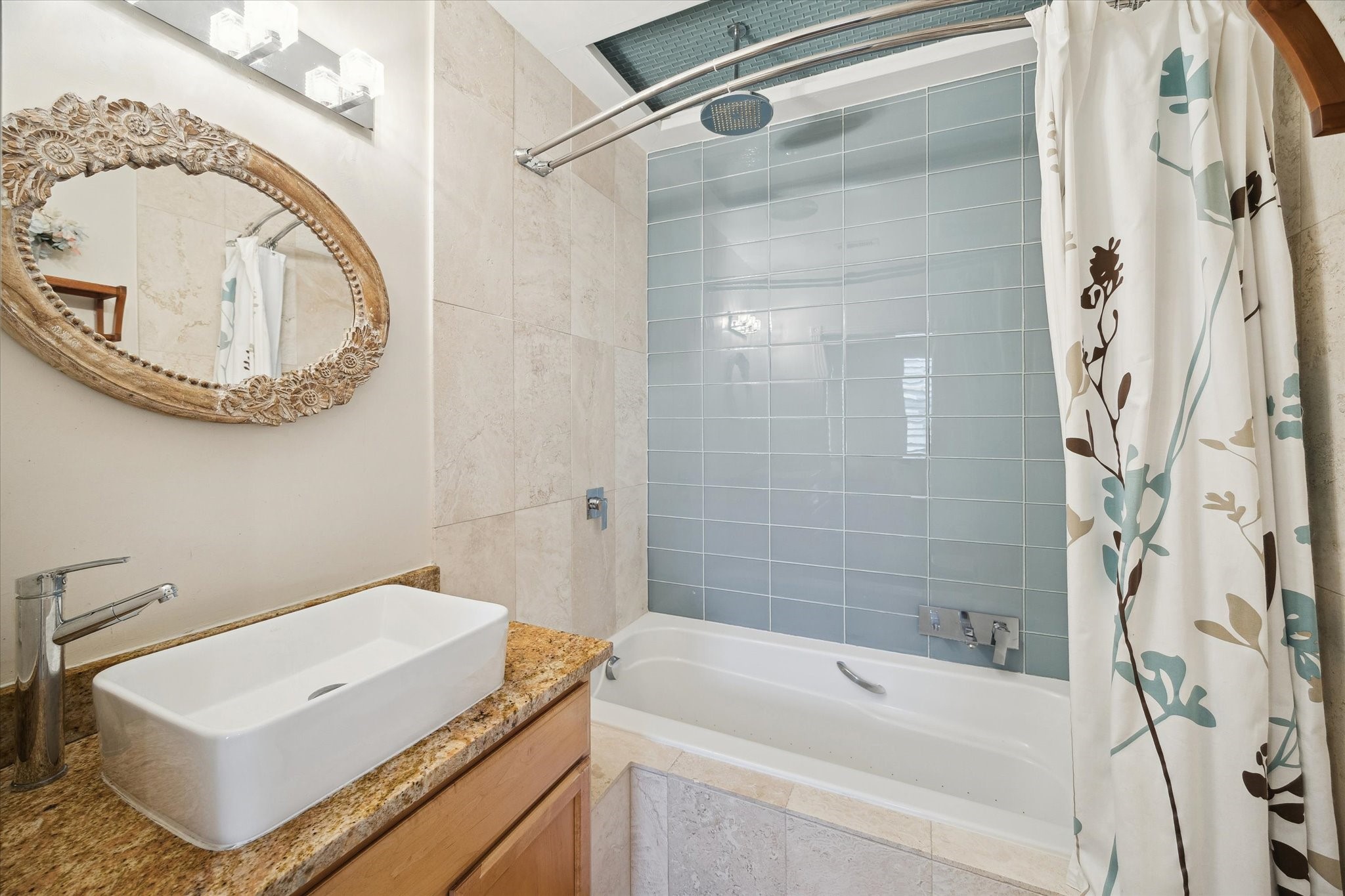 Secondary bathroom with modern design with a rectangular vessel sink, and a tub-shower combo with stylish blue-gray tile.