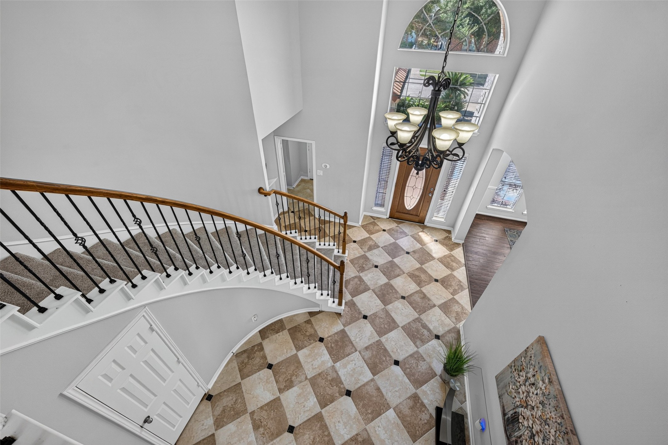 Looking down from above, this dramatic two-story foyer showcases an impressive sweeping curved staircase and elegant soaring ceilings that create an immediate feeling of grandeur.