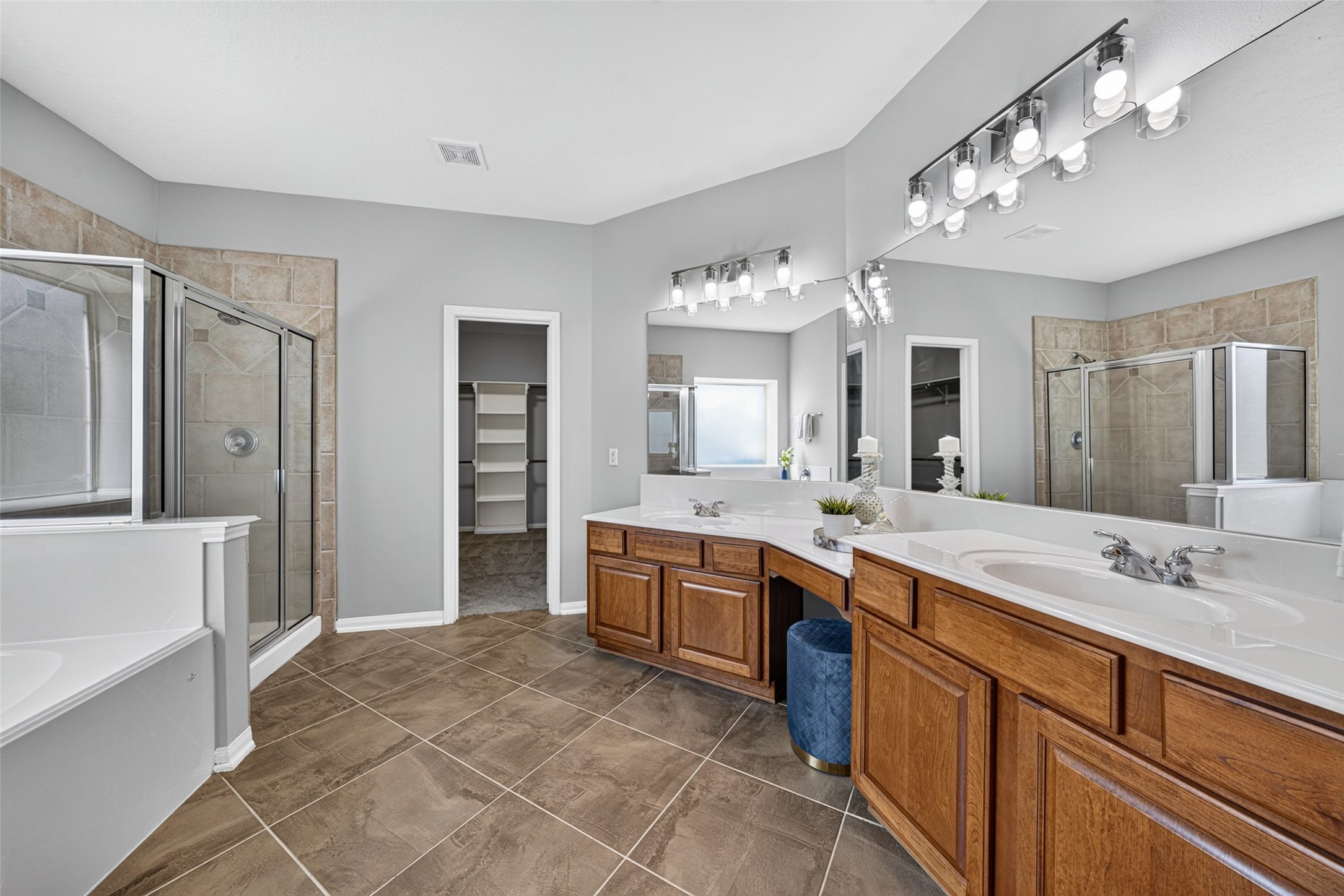 Designed as a serene, spa-like retreat, this luxurious main-floor bathroom features an expansive double-sink vanity with warm wood cabinetry and generous counter space.