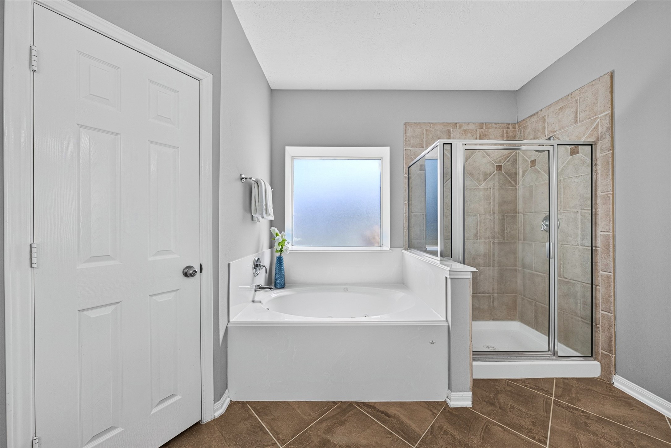 Step into the refreshing shower, or melt away the day's stress with a long soak in the deep soaking tub. Soothing neutral tile work and bright natural light create an inviting, peaceful oasis for your daily self-care routines.