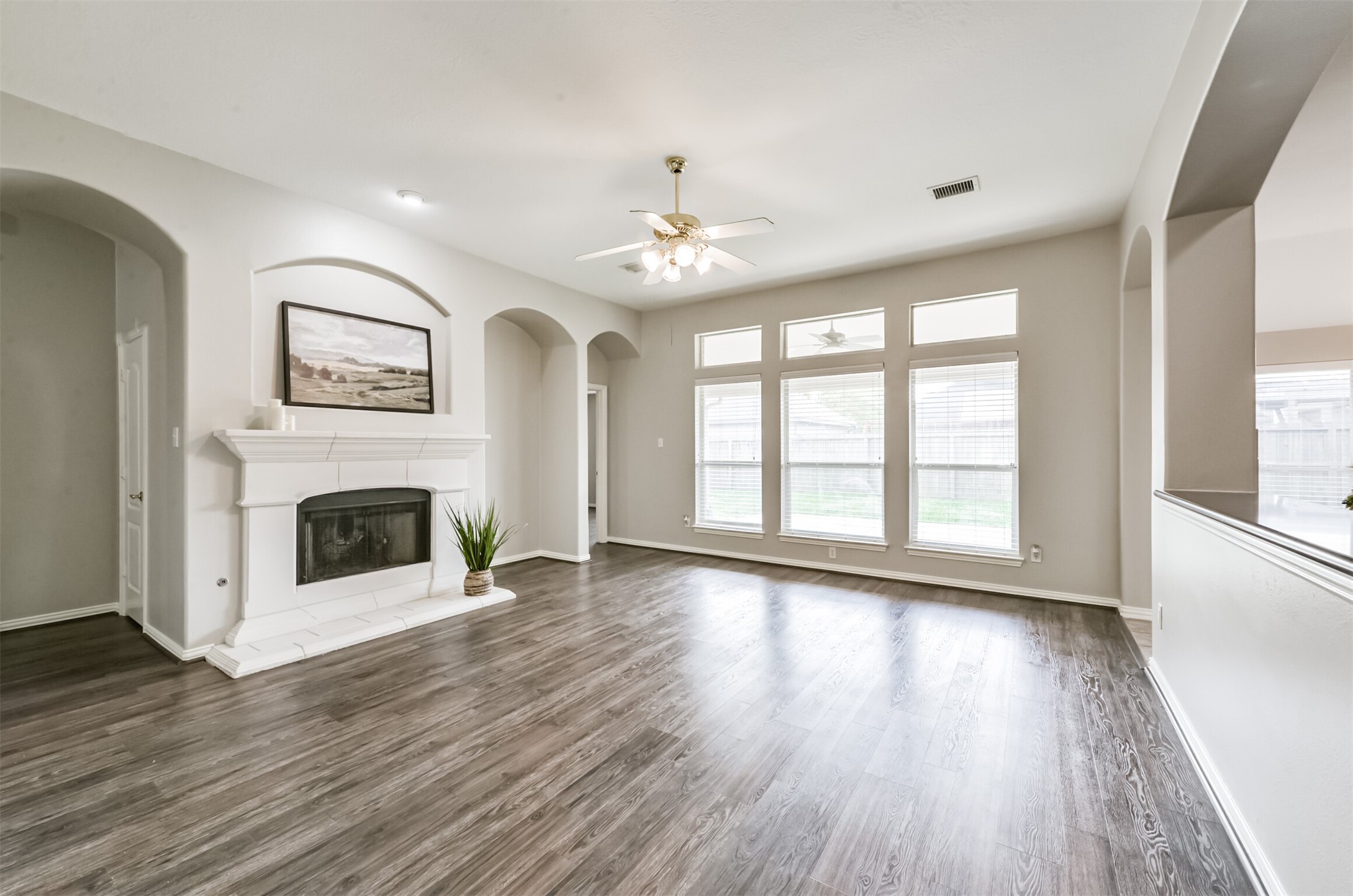 Spacious den with wall of windows, cast stone gas log fireplace, beautiful vinyl plank floors.  Den is open to kitchen.