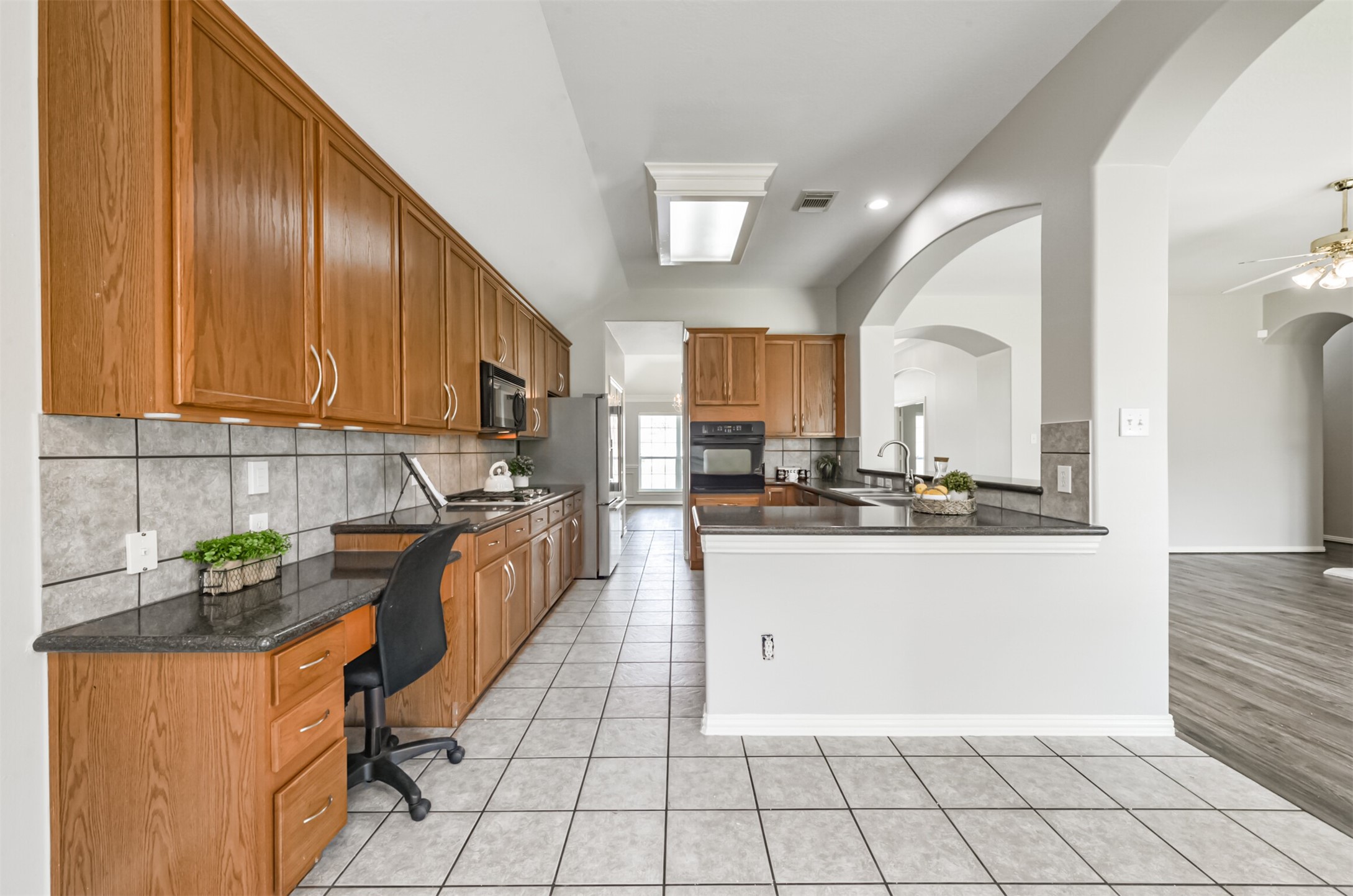 Plentiful kitchen cabinetry, desk, breakfast bar.
