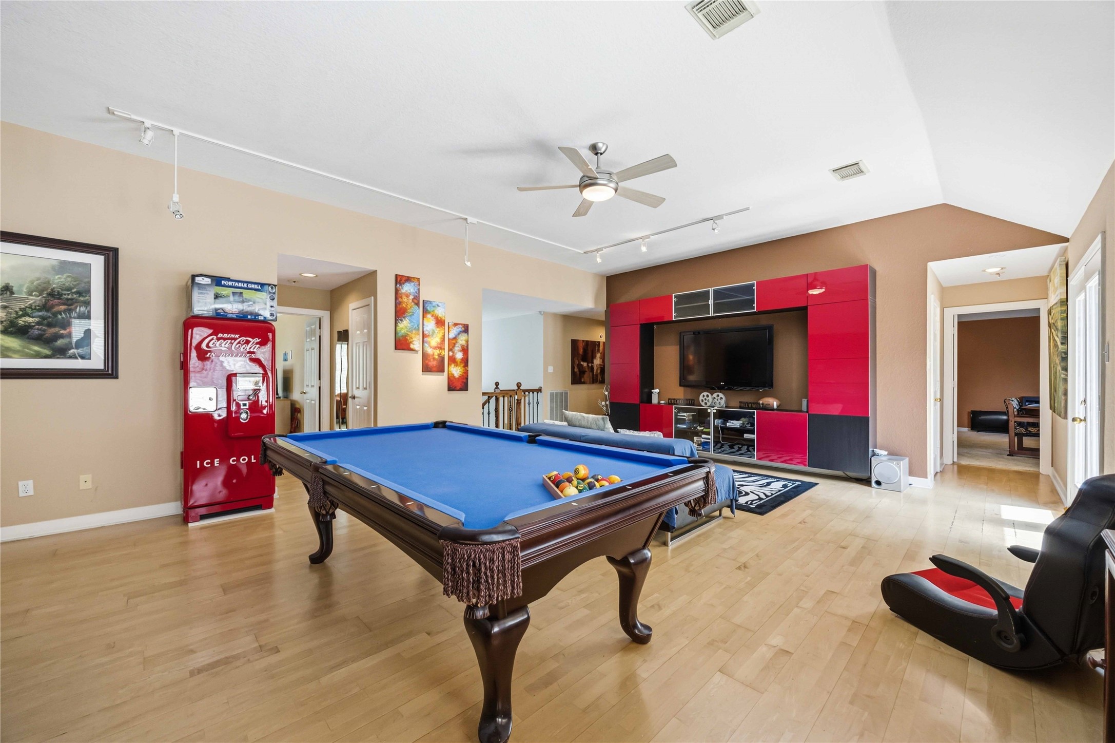 This versatile entertainment space features an open layout with recessed media wall alcoves, structured wall cutouts, and multiple doorways connecting to adjacent rooms.