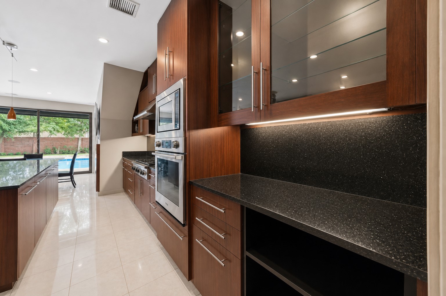 A dedicated butler's pantry or prep station offers under-cabinet lighting, glass-front upper displays, and built-in double ovens.