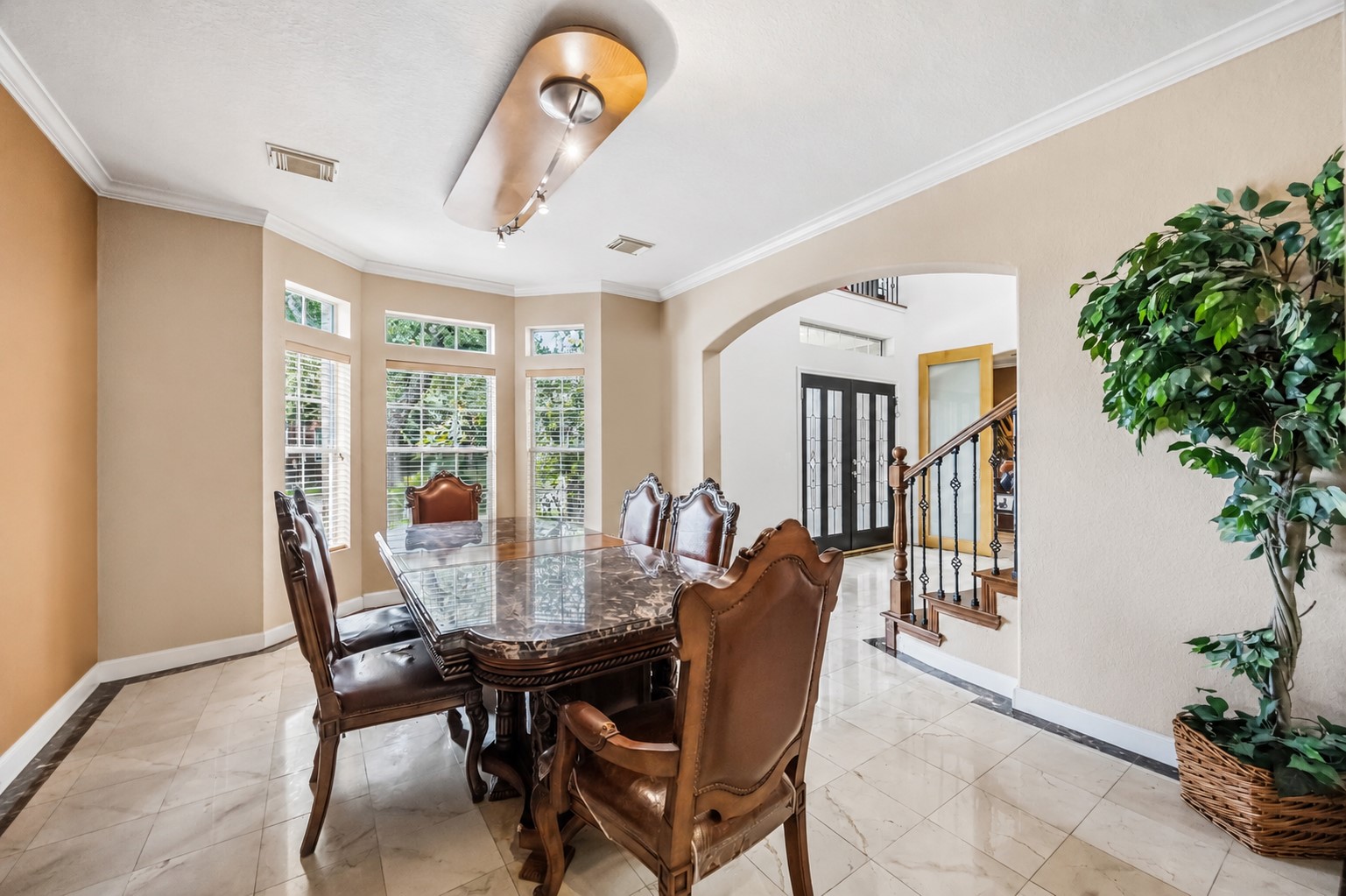 Highlighting an open architectural flow, this dining space includes a bay window alcove, a wide archway opening to the foyer, and a peek at the decorative staircase banister.