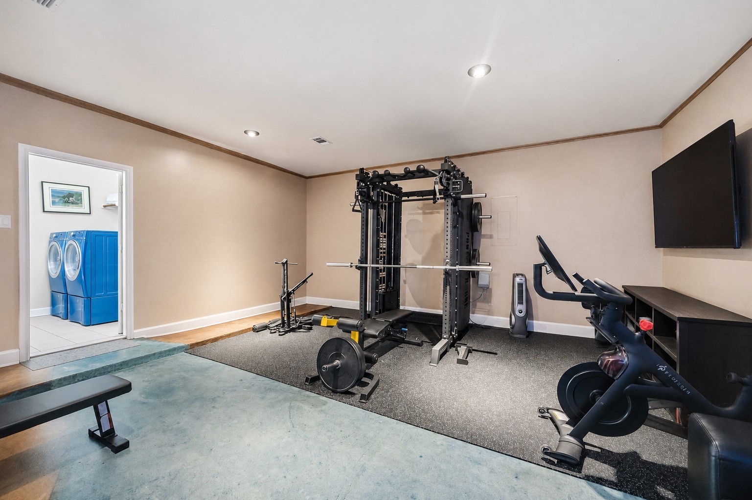 This multi-purpose bonus space can easily be used as a gym area or tailored to your preference, featuring recessed lighting, durable concrete-style flooring, and a wide doorway connecting to the laundry room.