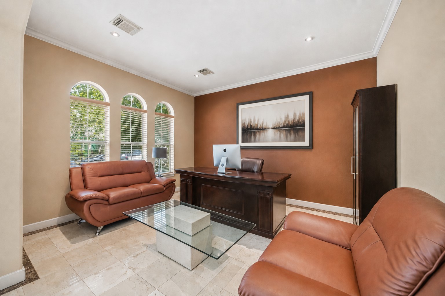 This versatile home office features three elegant arched front windows with built-in blinds, track lighting, and pristine tile floors.