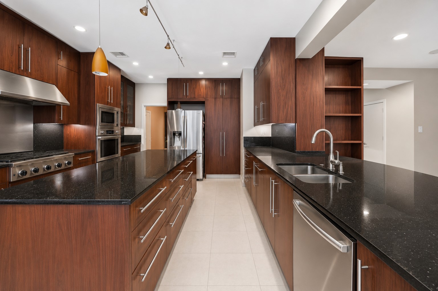 An under-mount double sink with a gooseneck faucet is integrated seamlessly into the long quartz-topped breakfast bar.