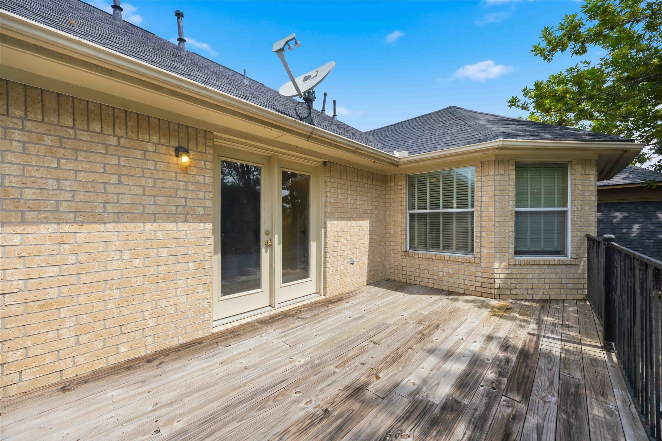 The private balcony structure showcases a light brick exterior wall, a sliding double-door entry, and classic window trim.