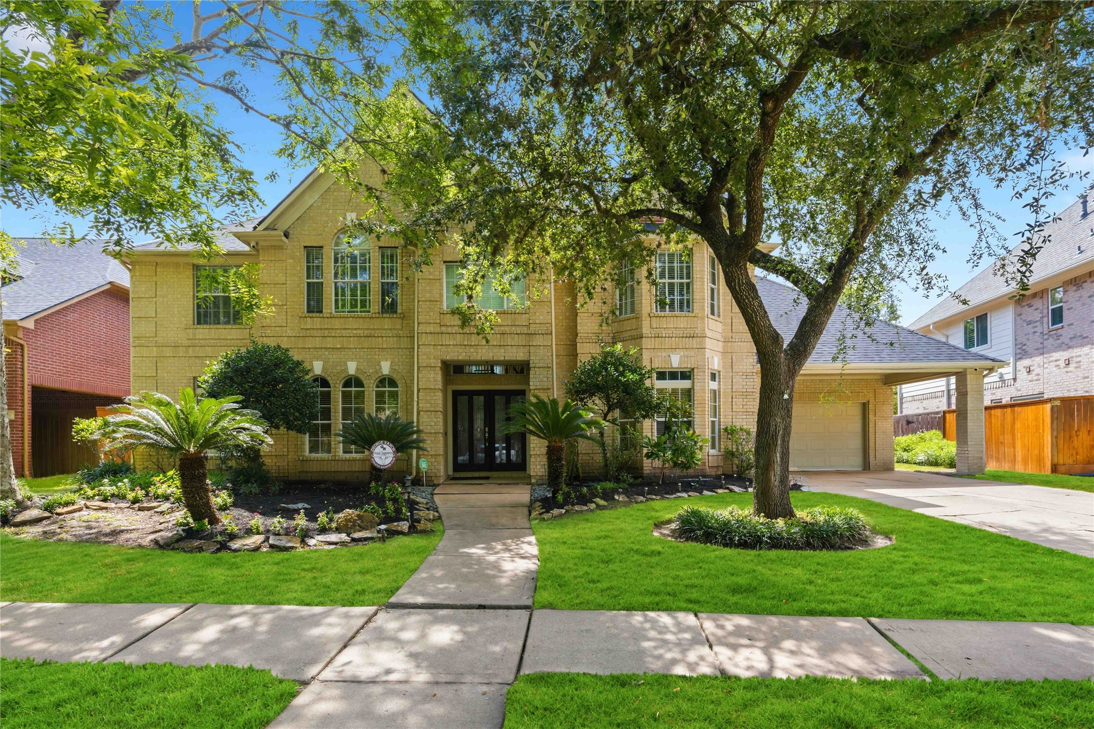 A striking brick exterior with elegant arched windows, an attached garage port, and a manicured lawn creates a timeless first impression and a picture-perfect welcome home.