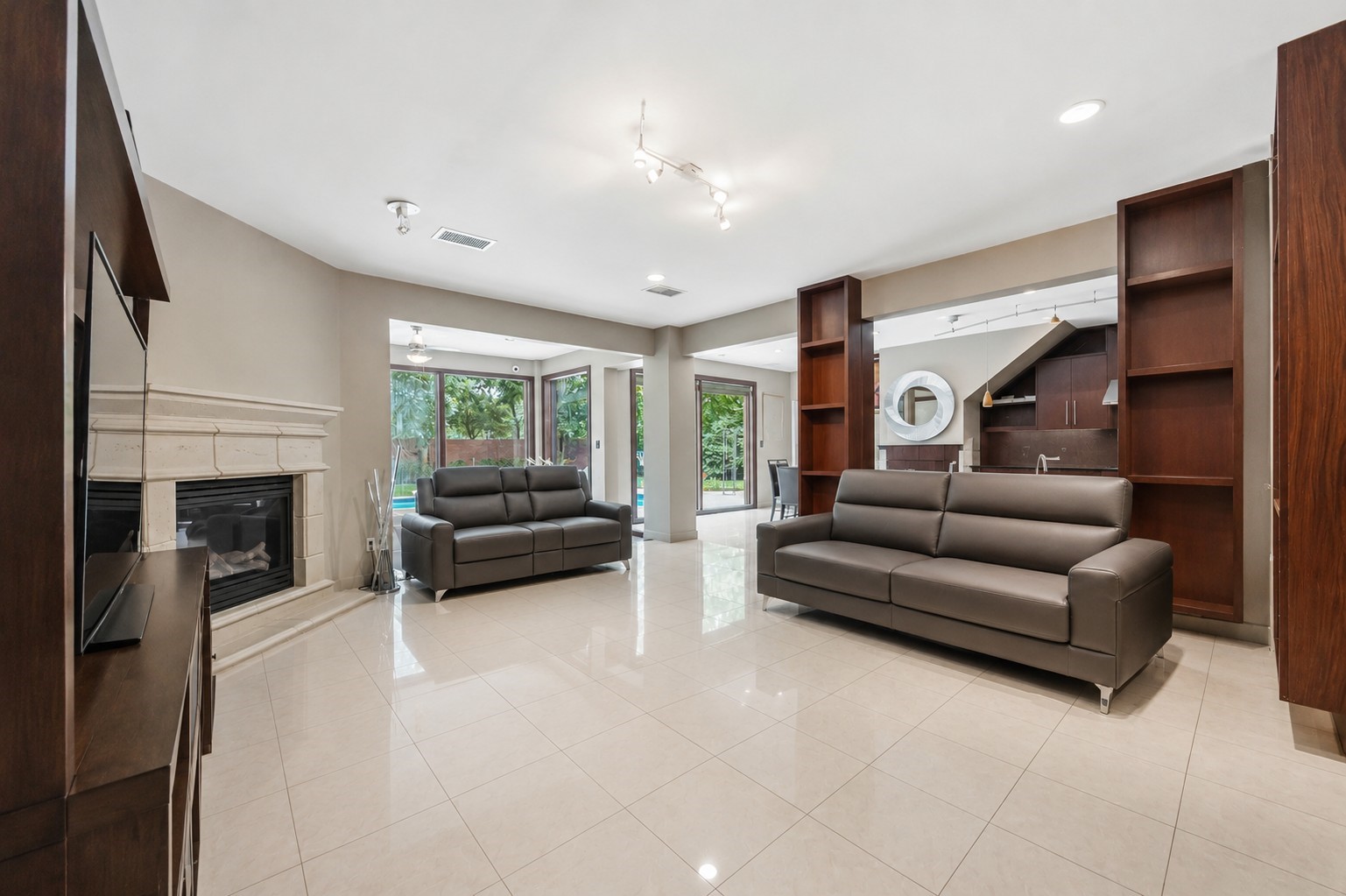 Large glass sliding doors frame views of the backyard pool, effortlessly connecting the open-concept living area to the outdoor spaces.