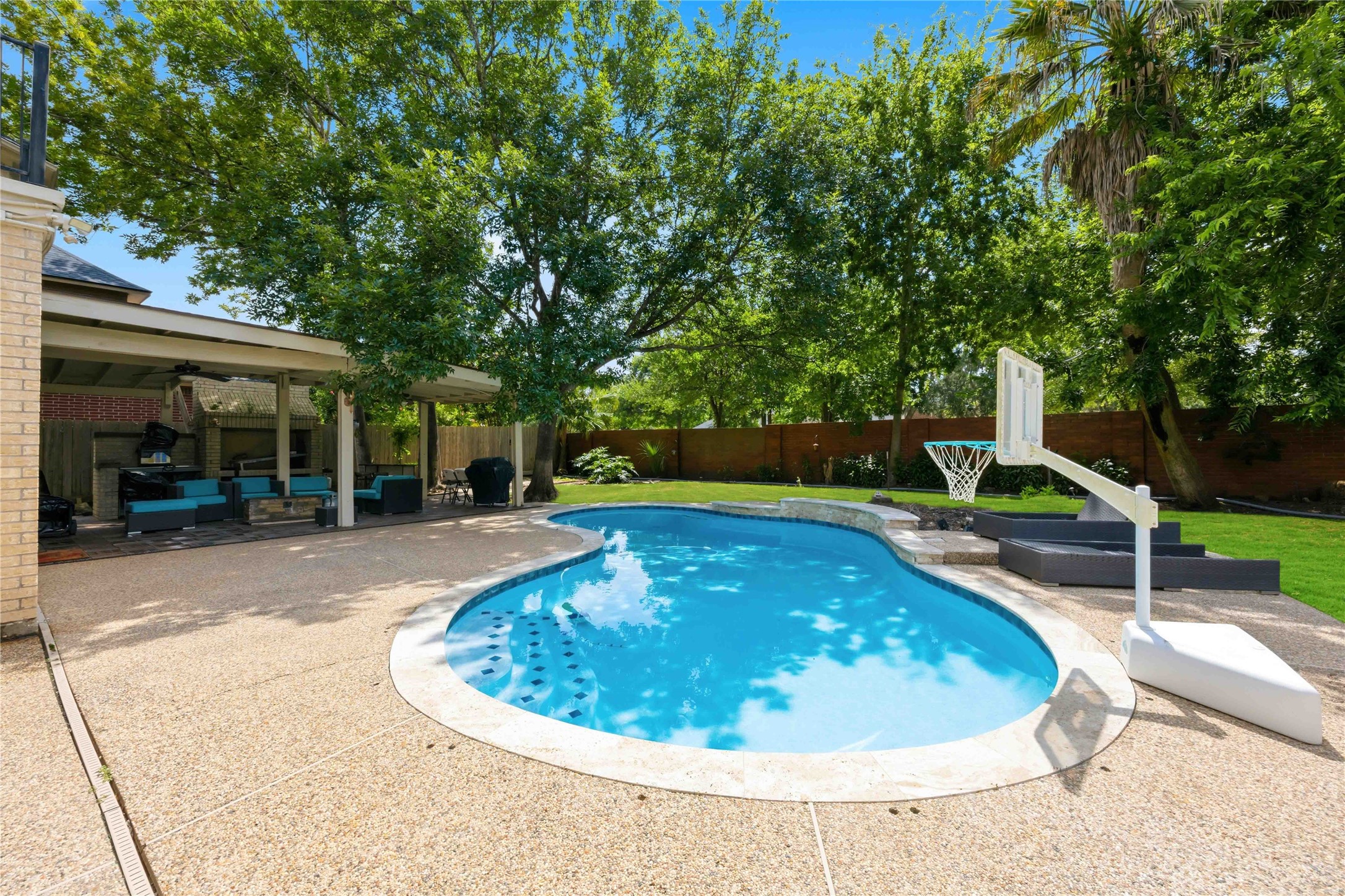 This outdoor oasis features a stone-lined pool deck that seamlessly transitions to a spacious covered entertainment pavilion.