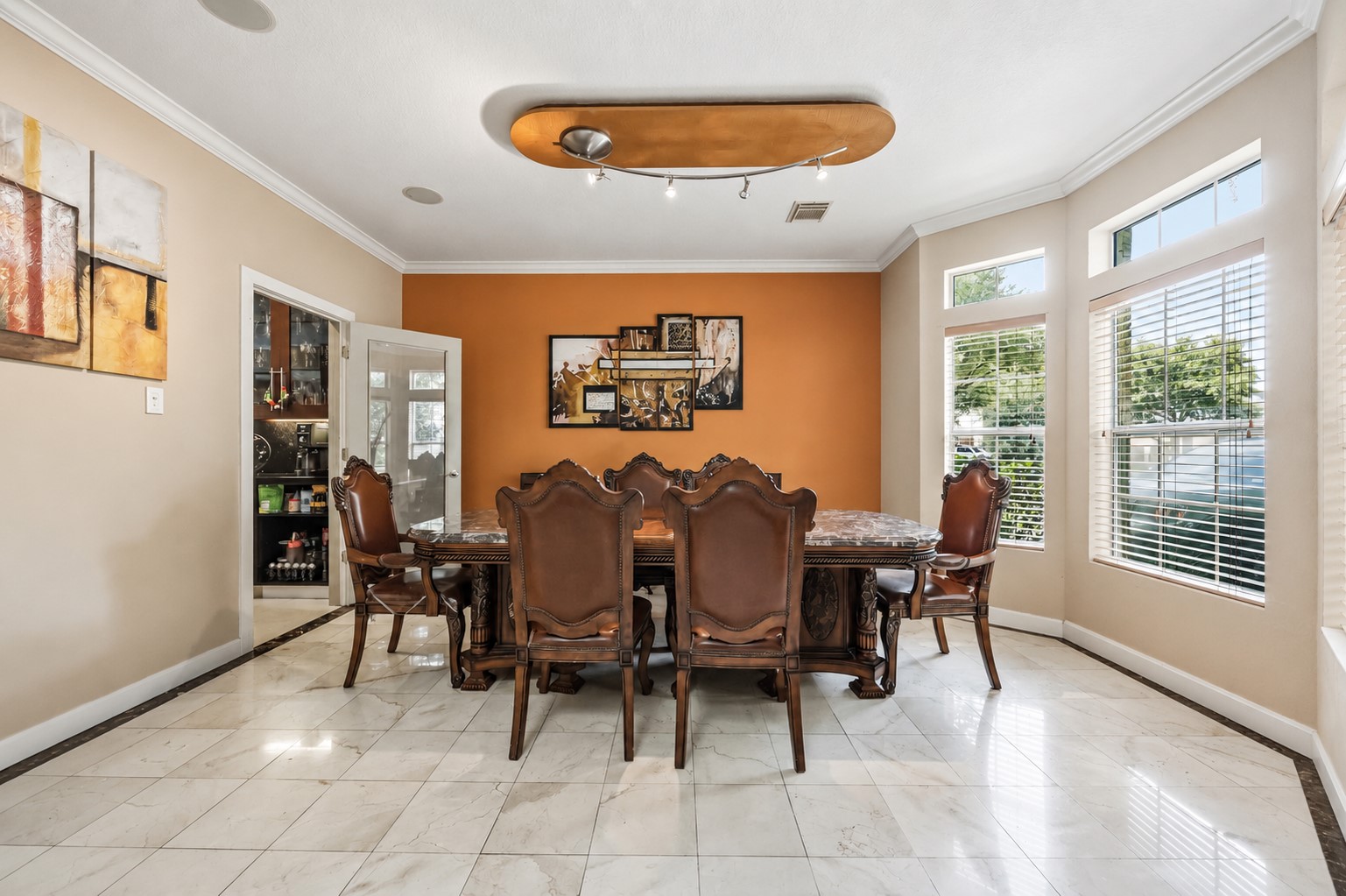 The formal dining room offers a smooth plaster ceiling with a modern track lighting fixture, crown molding, and large side windows overlooking the yard.