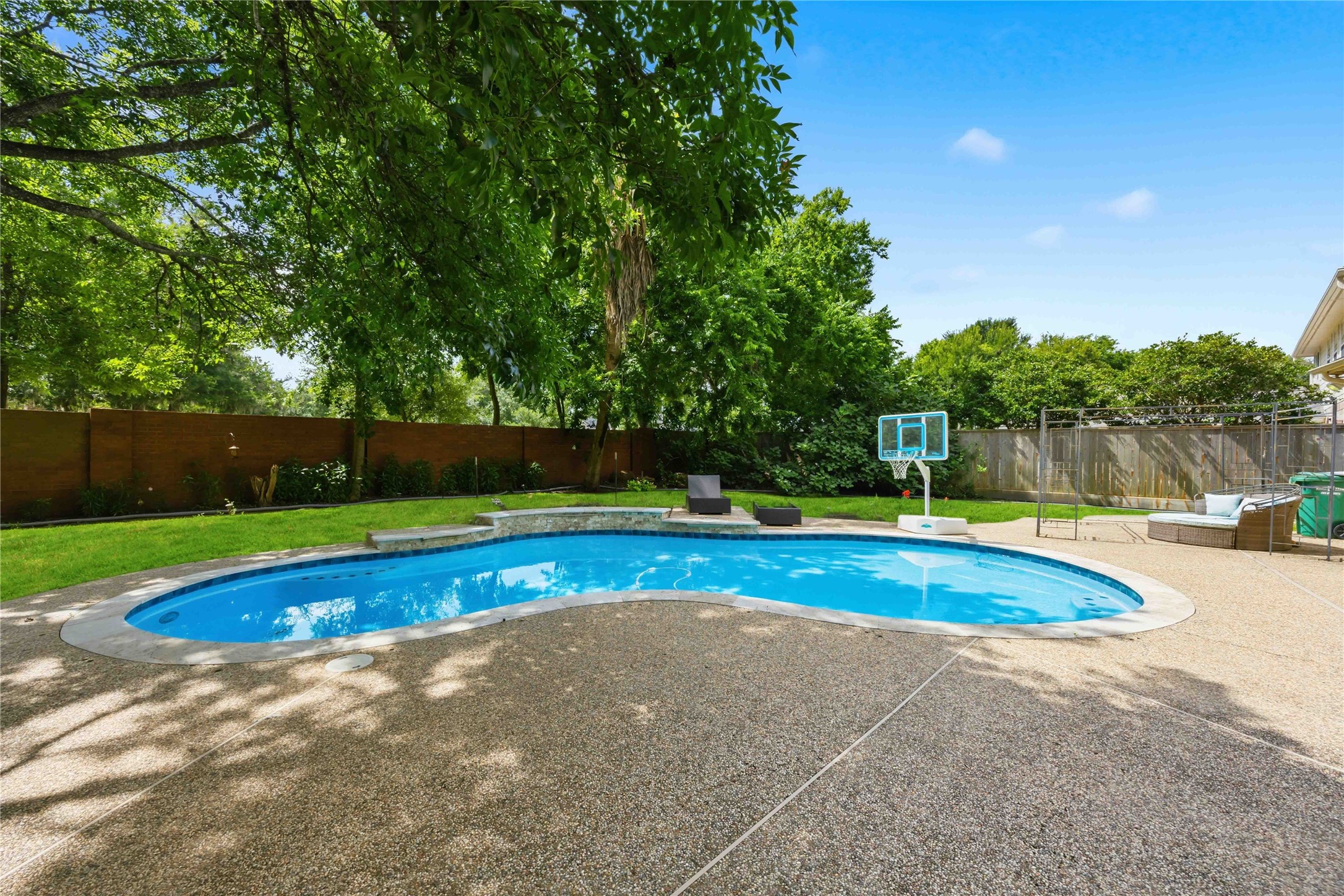 The resort-style backyard layout includes a multi-level pool coping design accented by tile work along the water line.