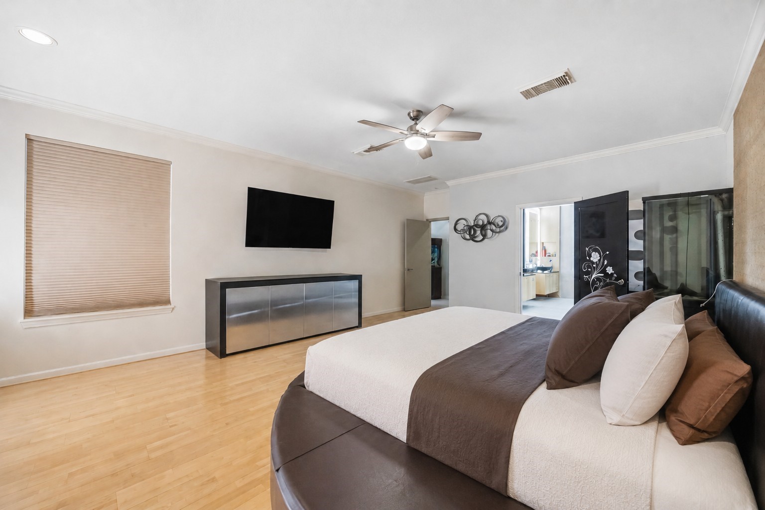 An alternate viewpoint of the main bedroom highlights a high ceiling with crown molding and an open doorway leading directly into the en-suite bathroom.