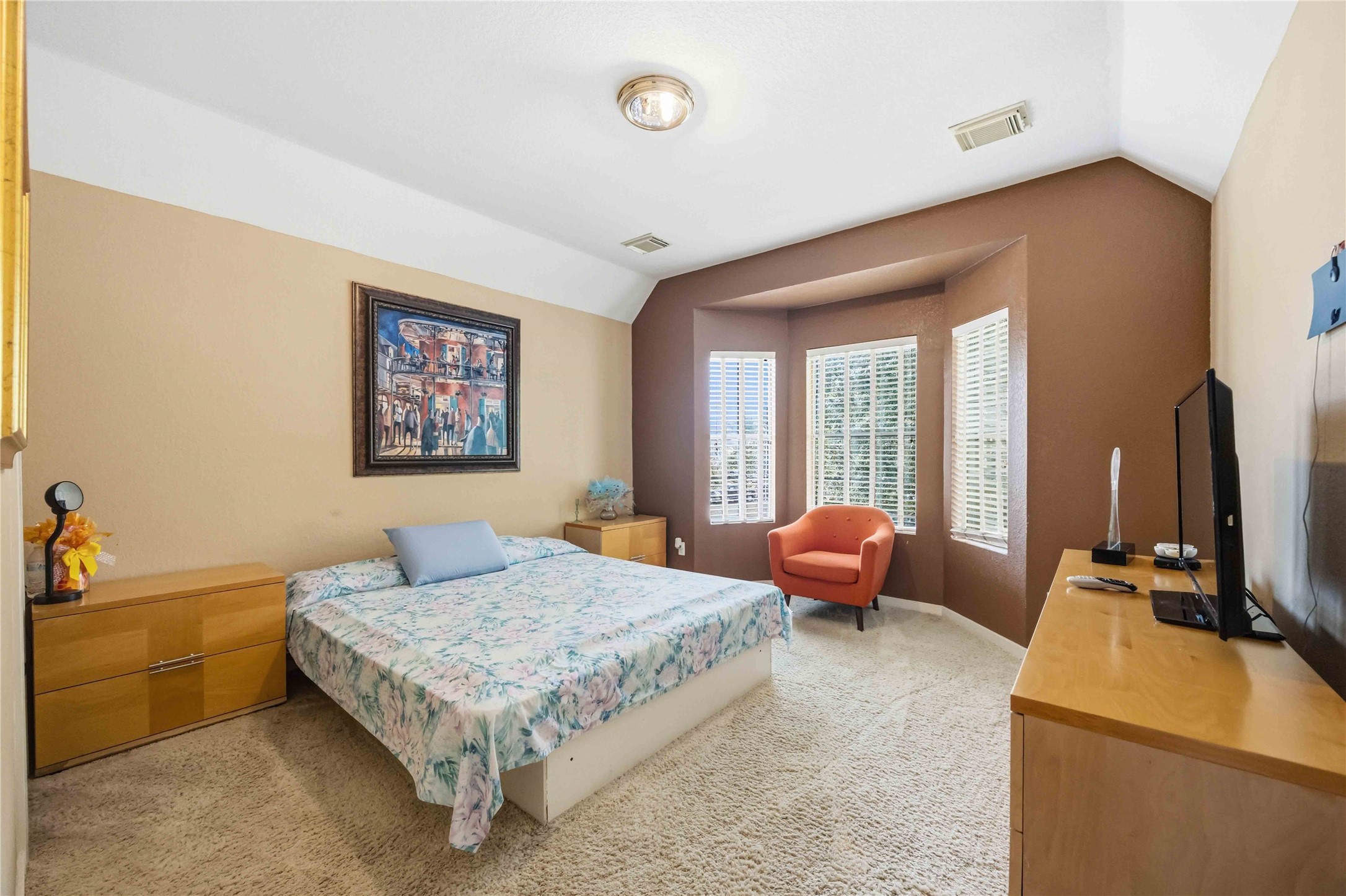 Cozy bedroom alcove with bay windows, overhead lighting, and warm tones.