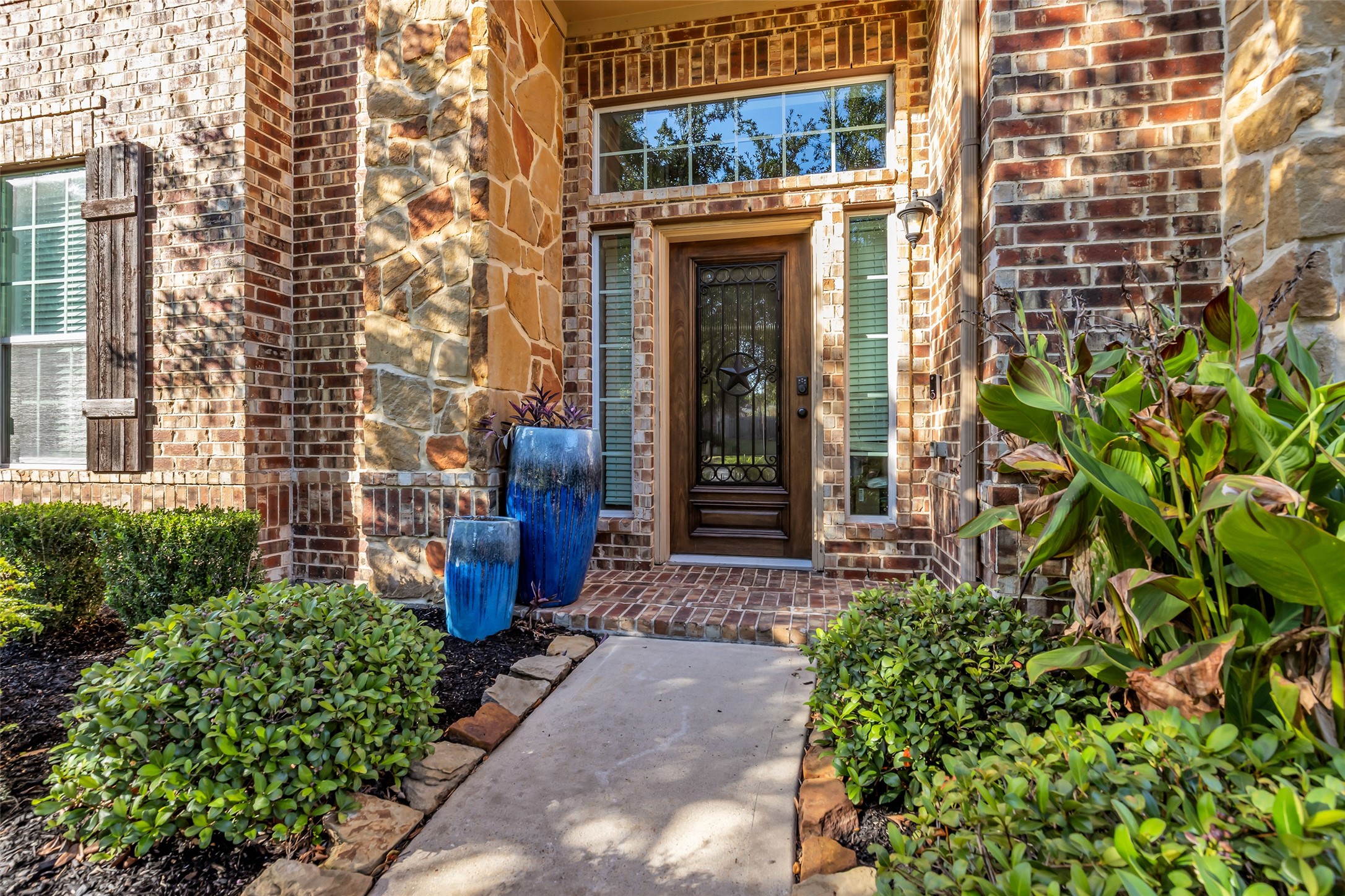 Charming brick and stone entryway with lush landscaping and elegant double door, creating a warm and inviting welcome. Charming brick and stone entryway with lush landscaping and elegant double door, creating a warm and inviting welcome.