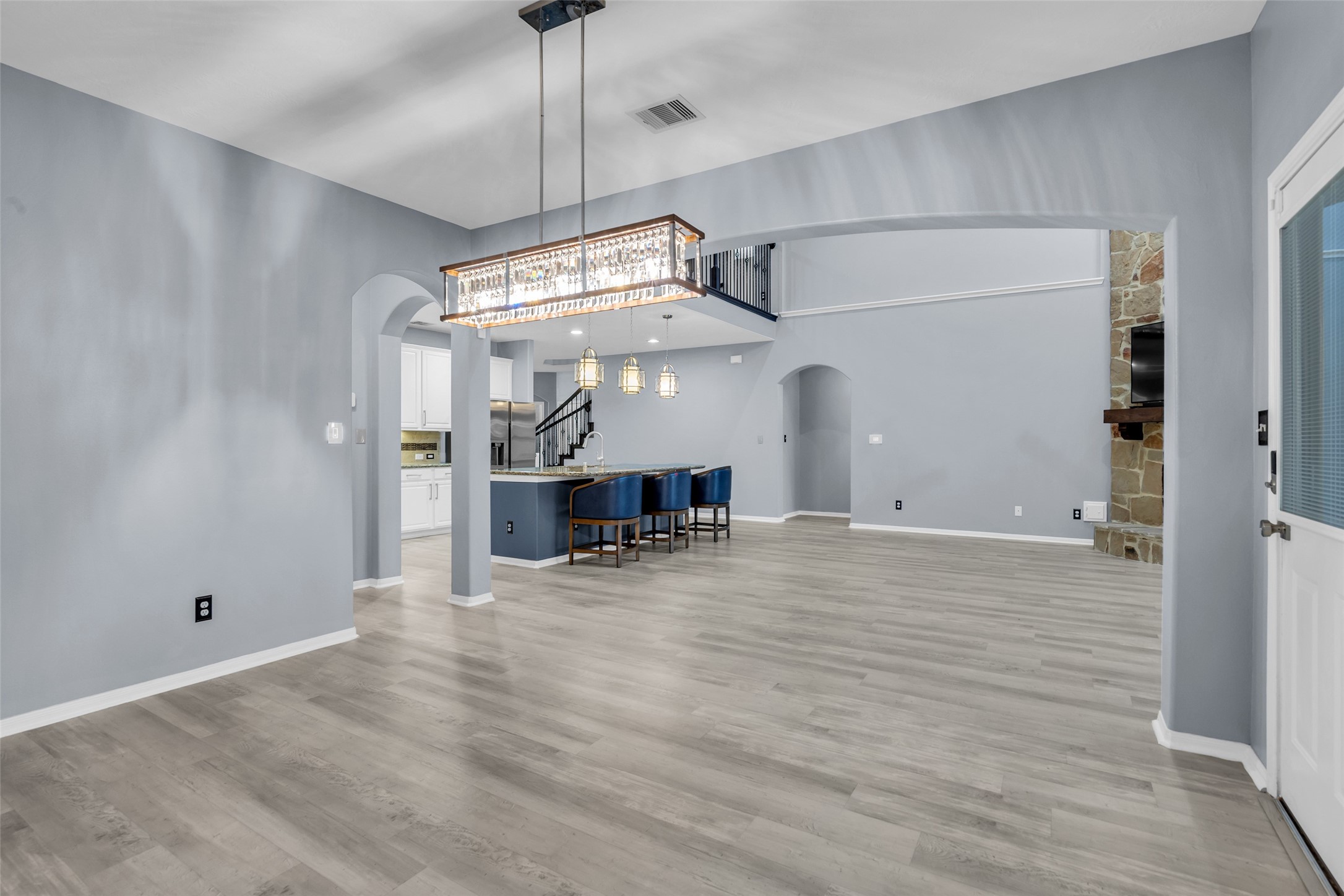 Breakfast area with spacious open-concept living area featuring elegant light fixtures, modern flooring, and a cozy stone fireplace, seamlessly connecting to a stylish kitchen with a breakfast bar.