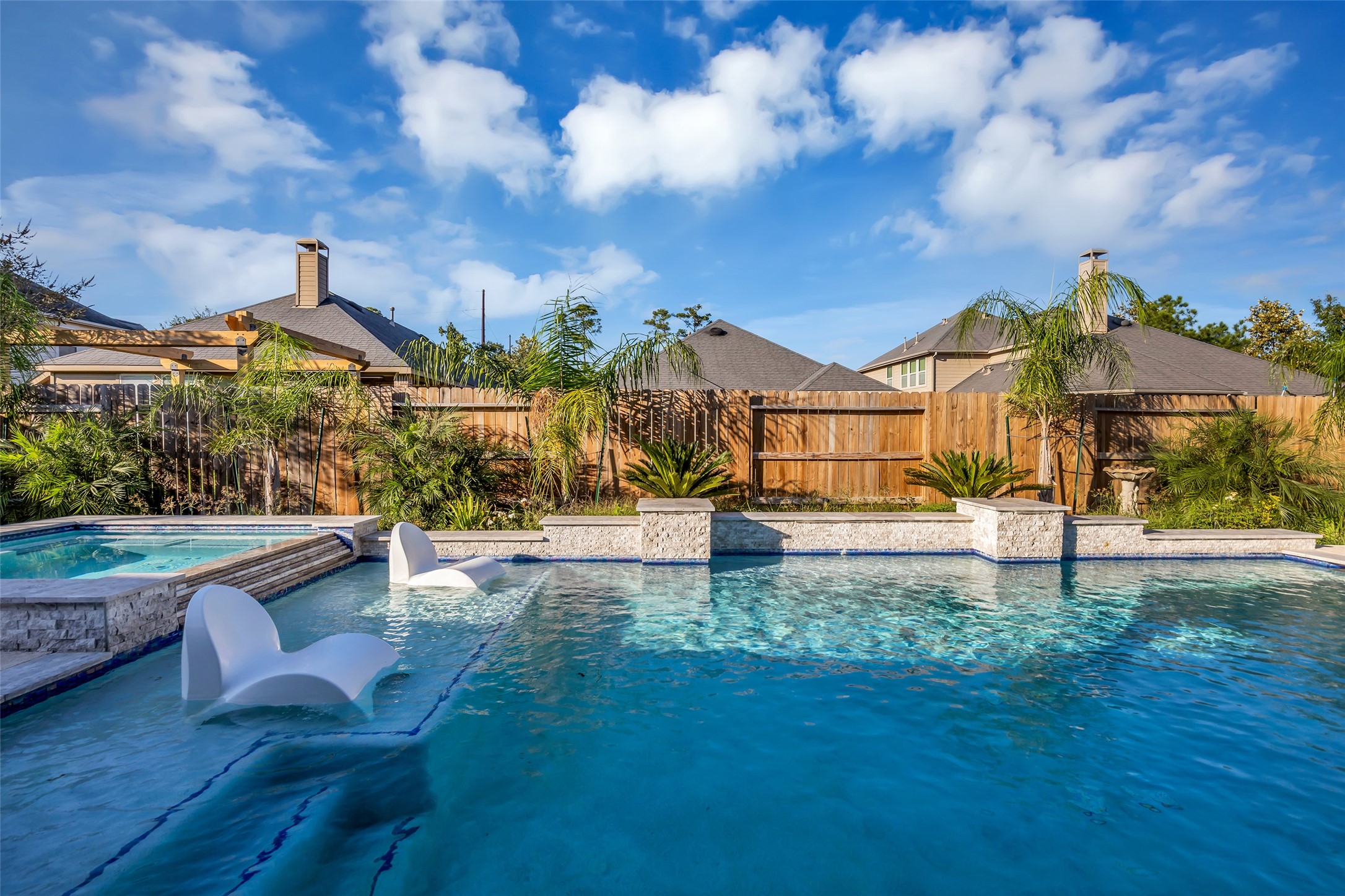 Experience resort-style living with a stunning backyard oasis featuring a sparkling pool, elegant stone accents, and lush tropical landscaping.