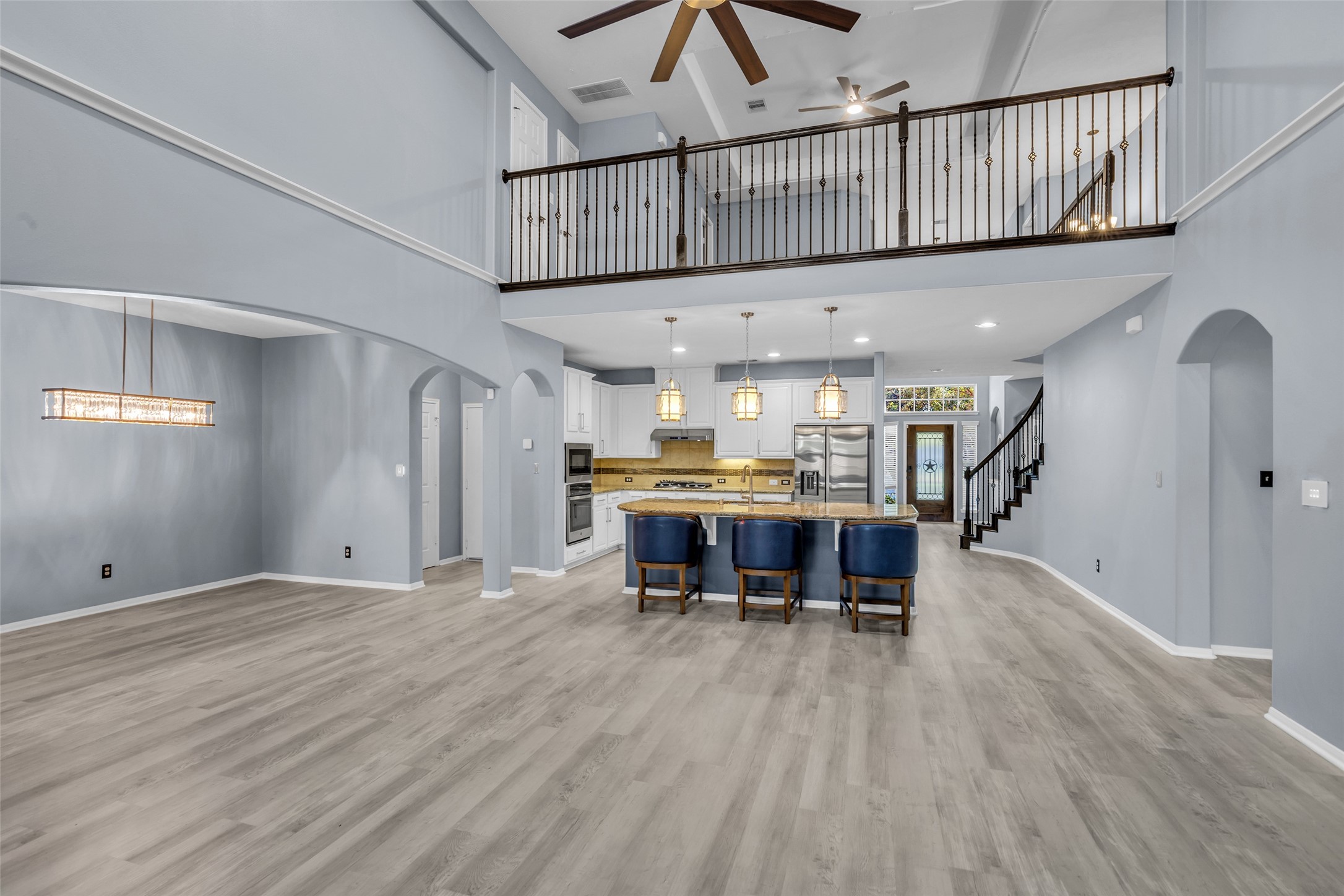 Stunning open-concept living area with high ceilings, elegant two-story design, and a modern kitchen featuring a large island with seating.