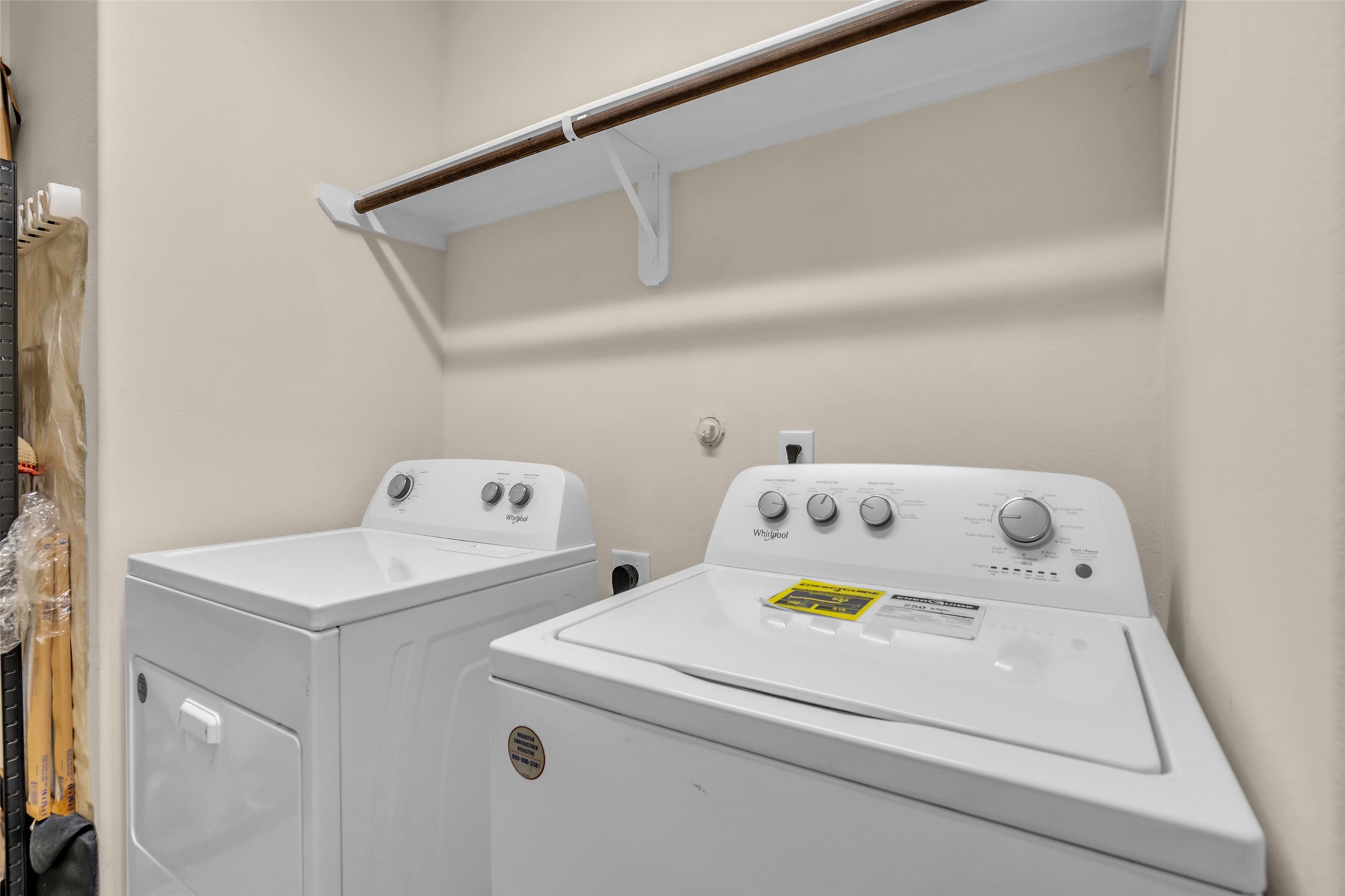 Convenient laundry area with modern washer and dryer, featuring overhead shelving for additional storage.