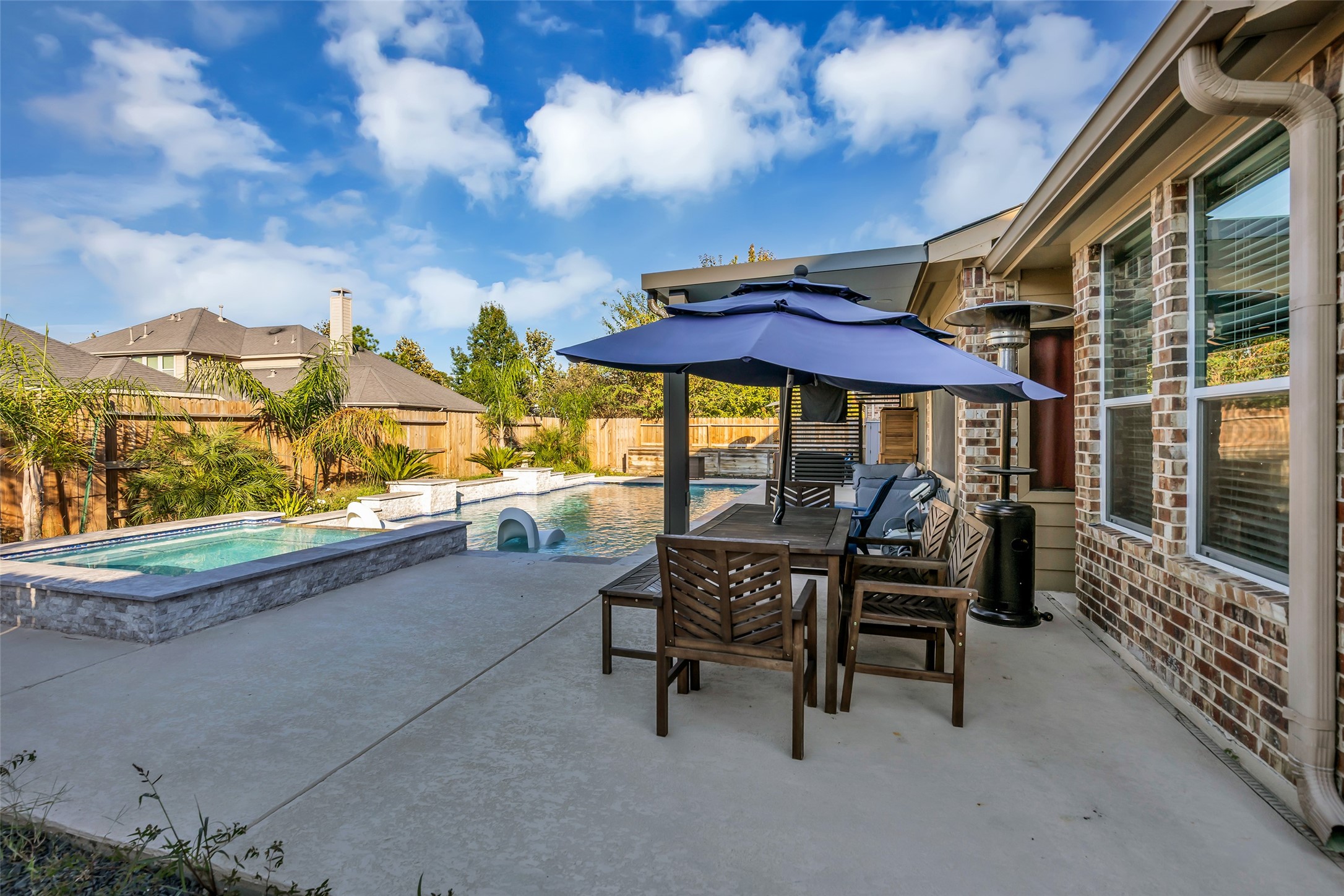 Relax in a stunning backyard oasis featuring a sparkling pool, spacious patio, and stylish outdoor dining area, perfect for entertaining or unwinding.