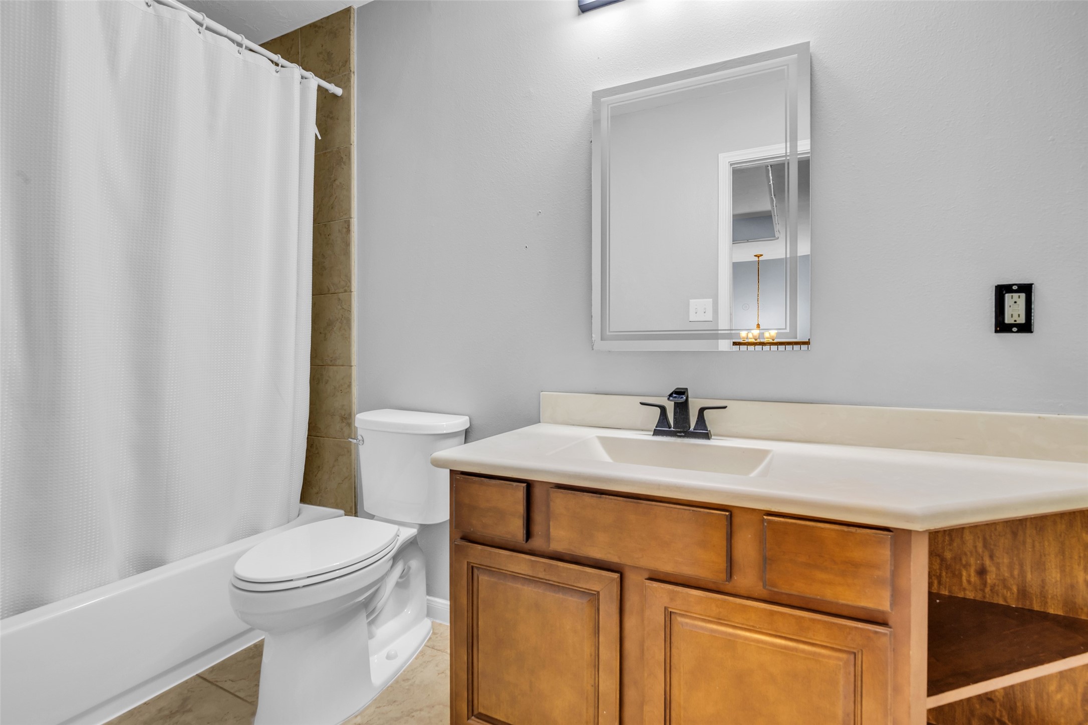 Upstairs secondary bathroom with sleek fixtures, a spacious vanity, and a clean white shower-tub combo.