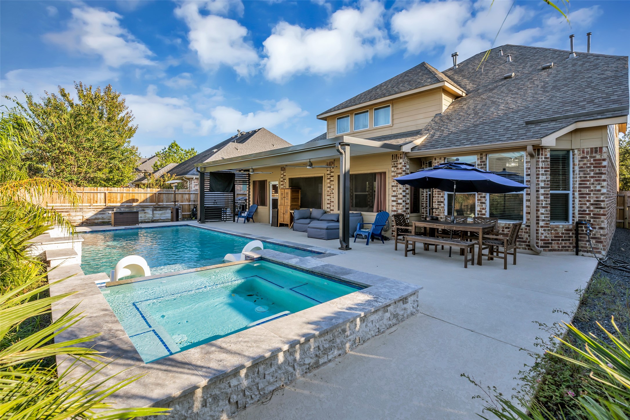 Stunning backyard oasis featuring a sparkling pool with attached spa, spacious patio with outdoor seating, and a shaded dining area perfect for entertaining. Stunning backyard oasis featuring a sparkling pool with attached spa, spacious patio with outdoor seating, and a shaded dining area perfect for entertaining.
