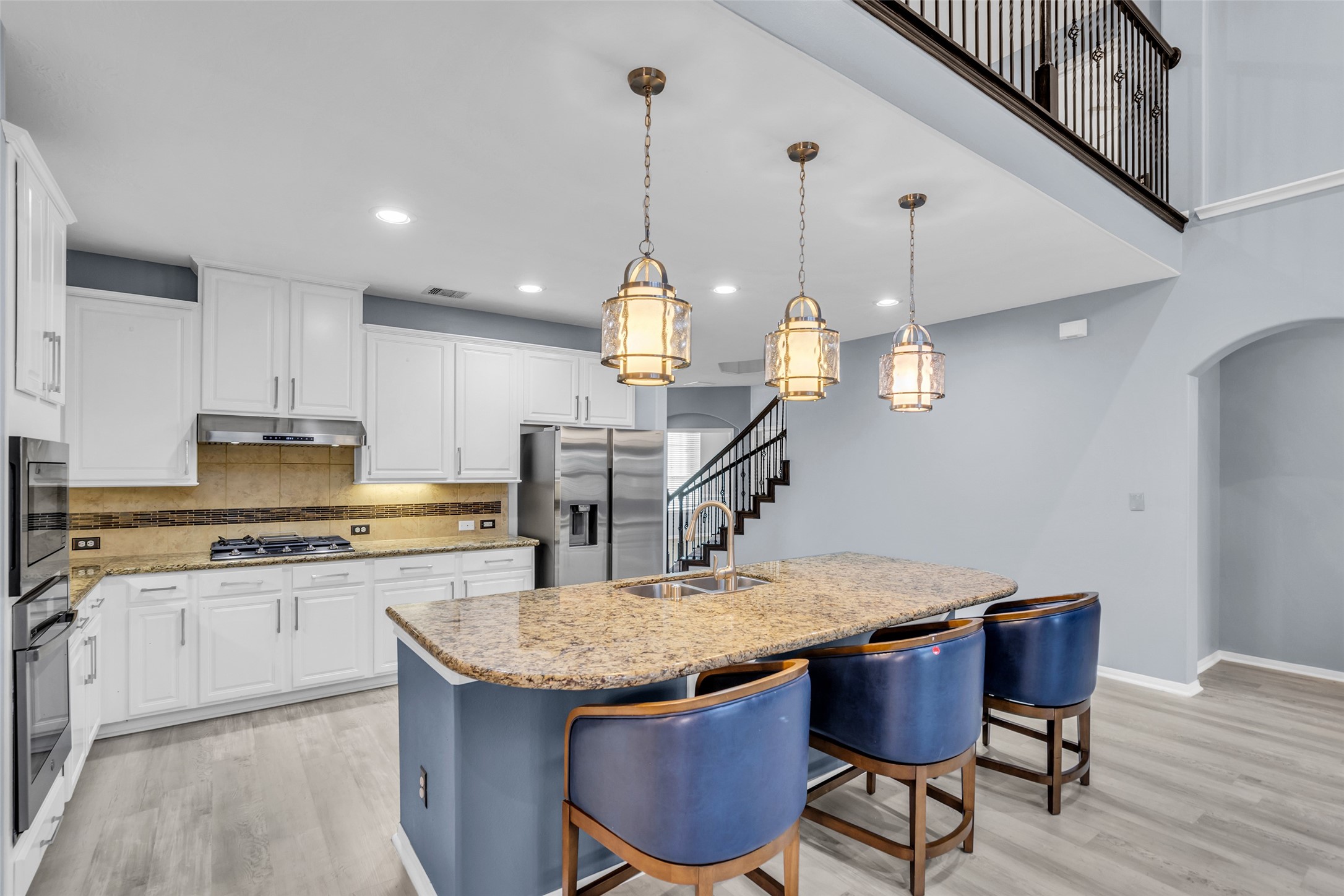 Modern kitchen with a spacious island, elegant granite countertops, and stylish pendant lighting, complemented by sleek stainless steel appliances and crisp white cabinetry.