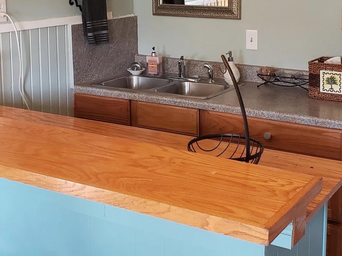Charming and functional kitchen in the Laurel Anne featuring a sleek double sink, cozy wooden countertops, and stylish cabinetry, perfect for culinary enthusiasts.